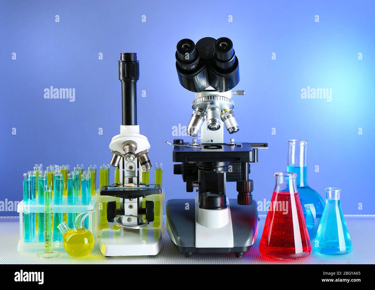 Microscopios y tubos de ensayo sobre mesa, sobre fondo de color Foto de stock