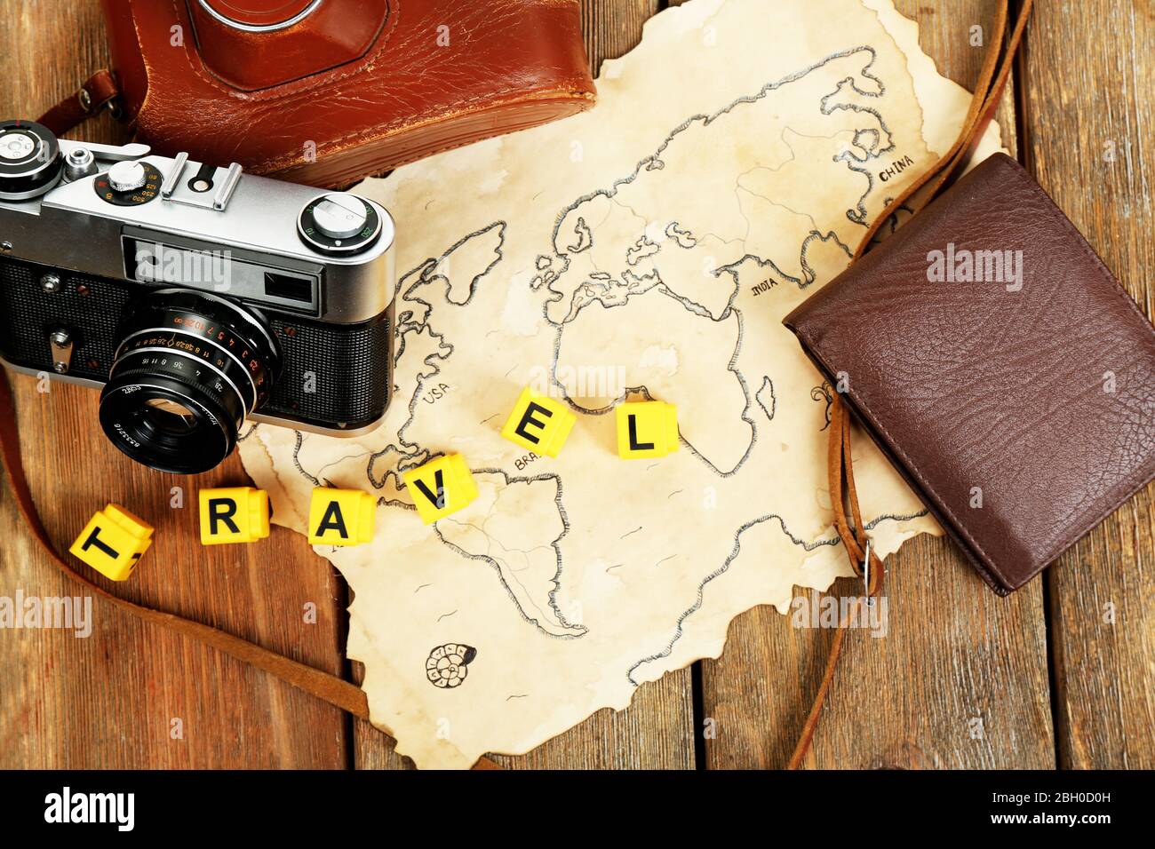 Cámara retro en mapa del mundo con palabra Viajes sobre fondo de mesa de madera Foto de stock