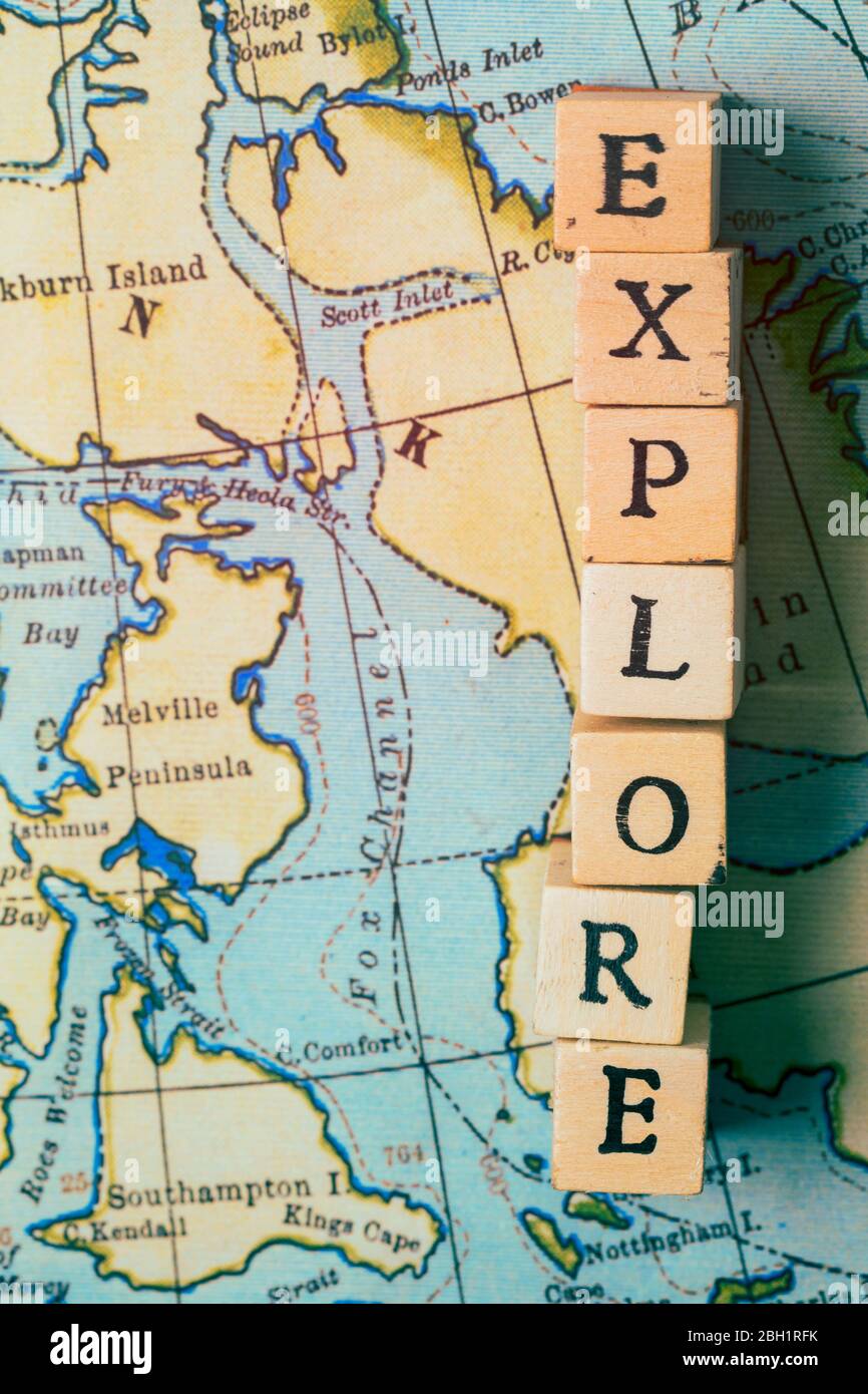 Explore la palabra escrita en bloques de madera en un mapa de viaje clásico Foto de stock