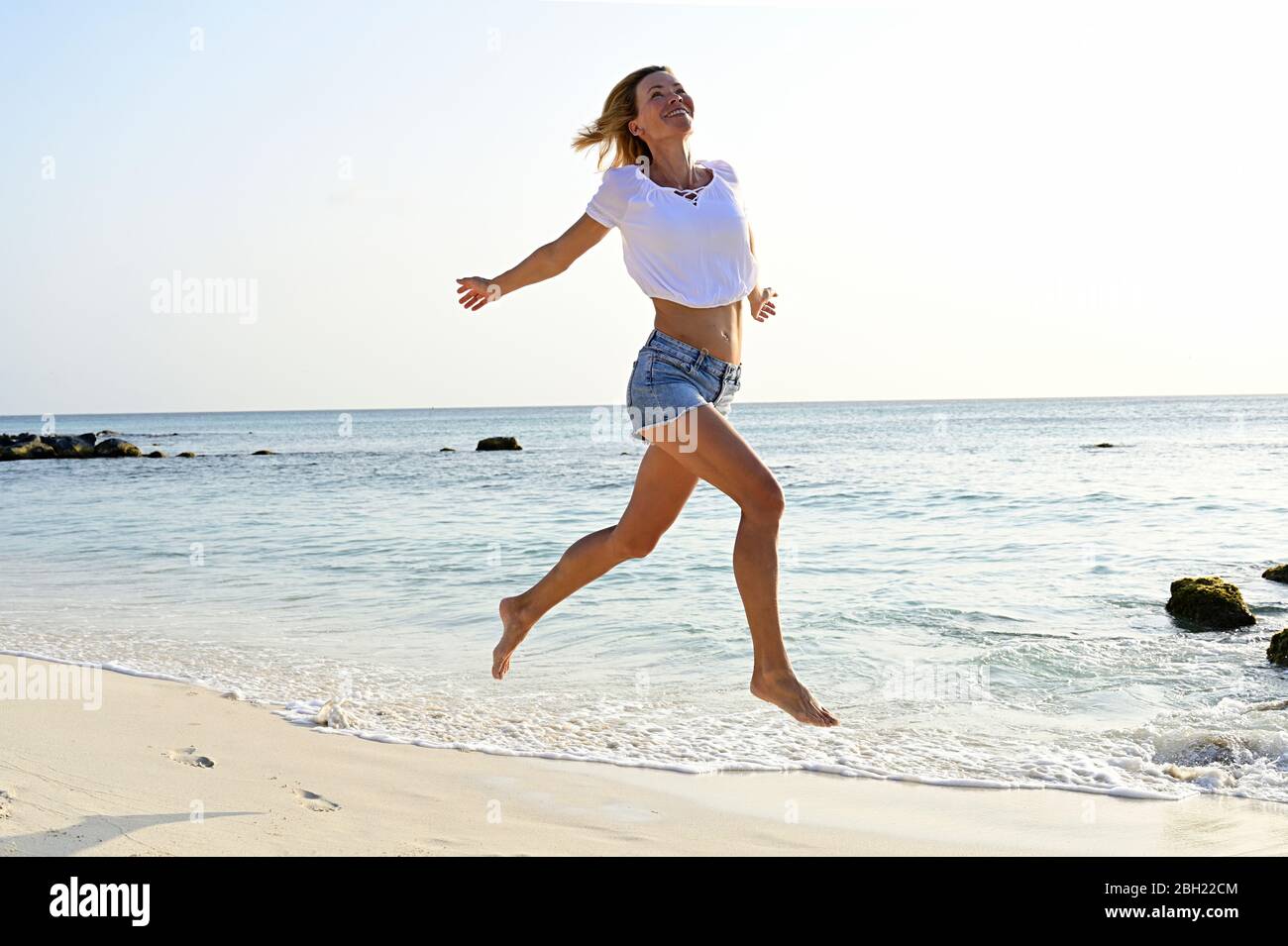 Hermosa mujer corriendo y saltando por alegría en la playa Fotografía de  stock - Alamy