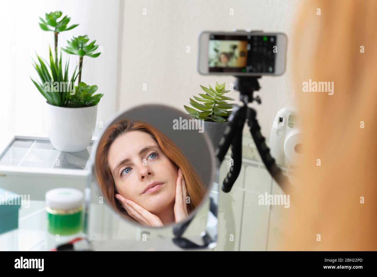 Mujer joven filmando su rutina de belleza en casa Foto de stock