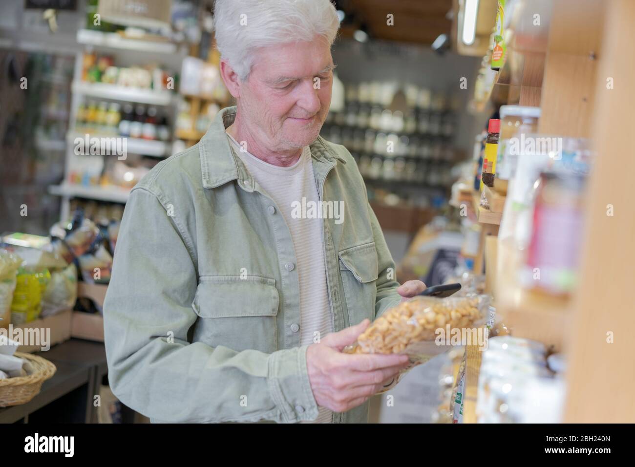 Hombre mayor comprando comestibles en una pequeña tienda de alimentos Foto de stock