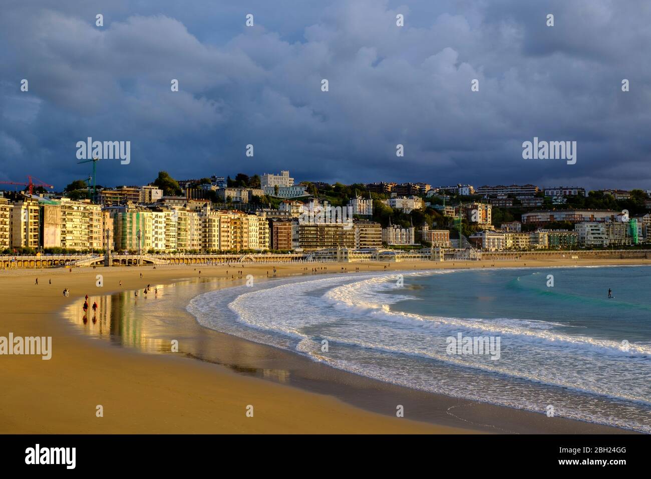 España, Gipuzkoa, San Sebastián, nubes de tormenta sobre la playa de arena de la Bahía de la Concha con edificios de la ciudad en el fondo Foto de stock