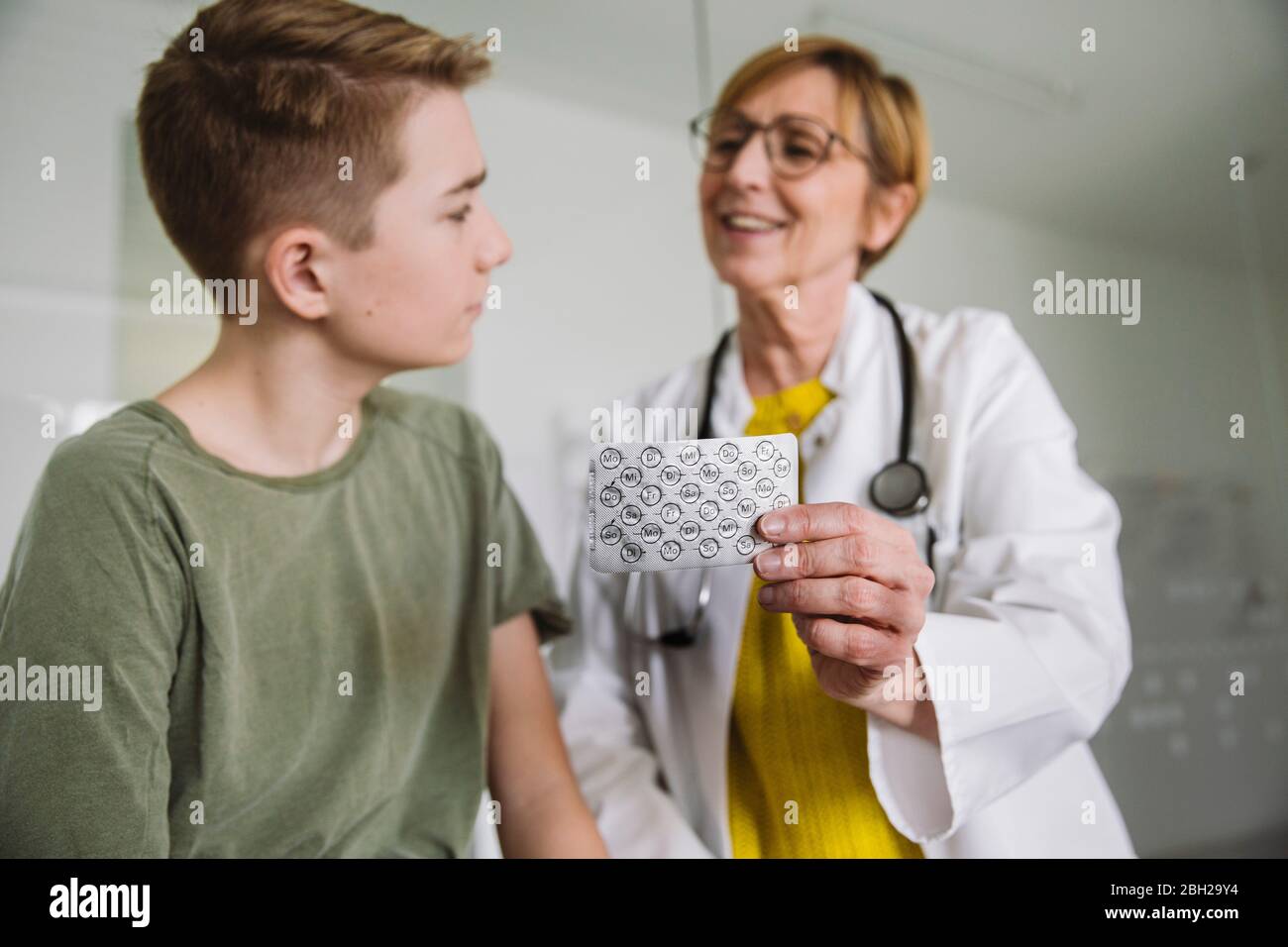 Médico explicando medicamentos a un adolescente en la práctica médica Foto de stock