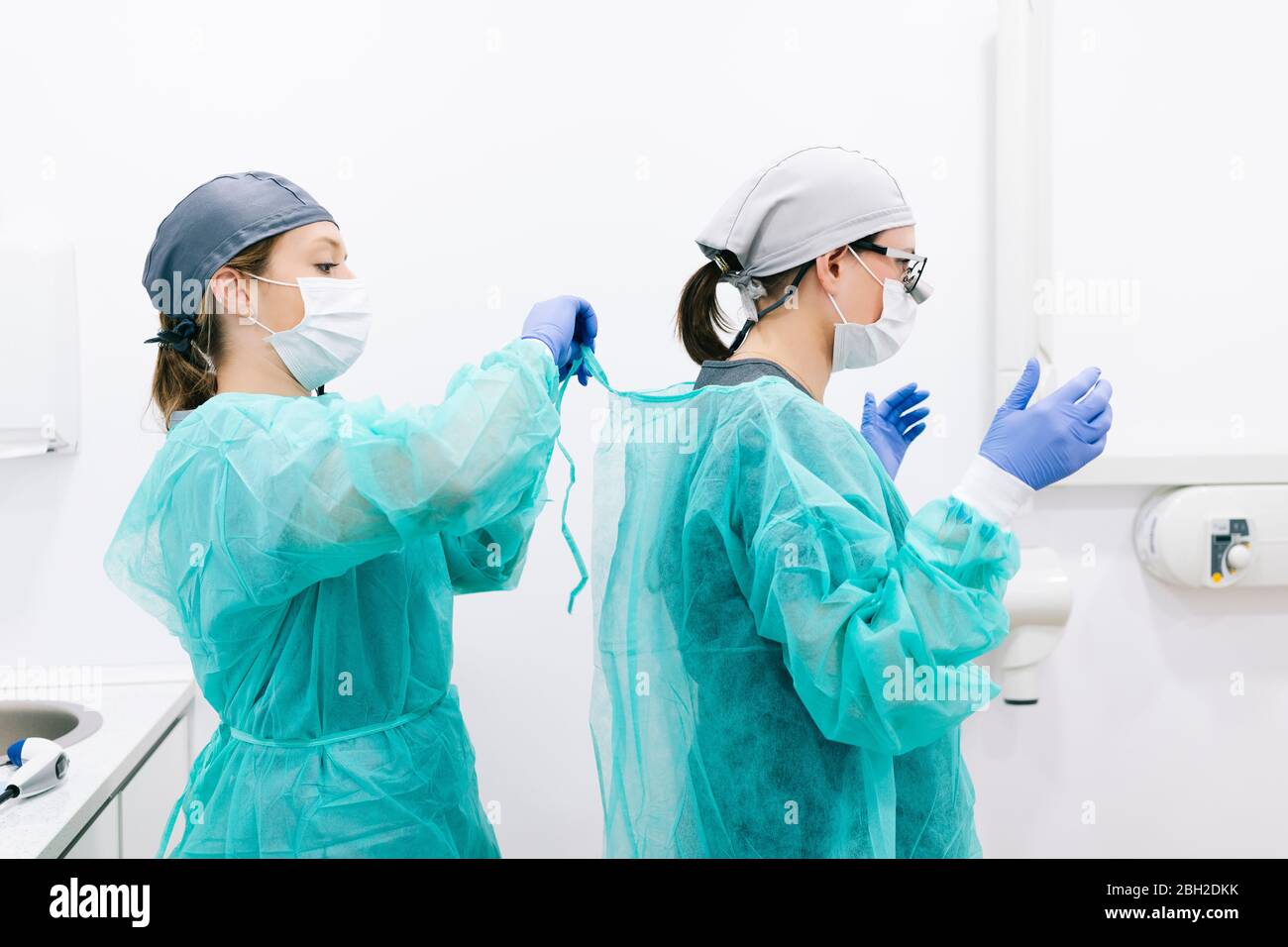 Dos dentistas poniendo ropa protectora estéril Foto de stock