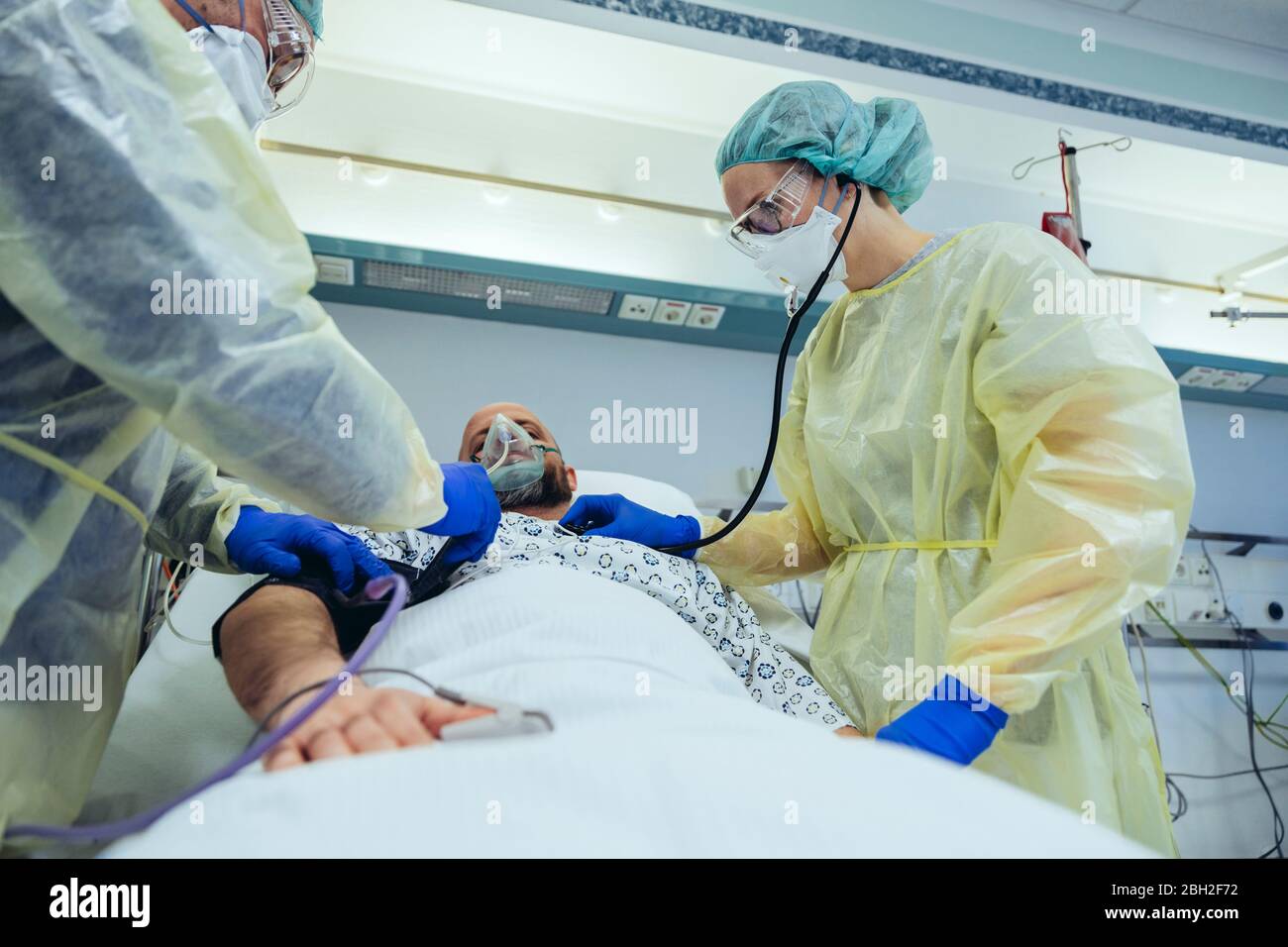 Médicos que atienden a pacientes en la unidad de cuidados de emergencia de un hospital con equipo respiratorio Foto de stock