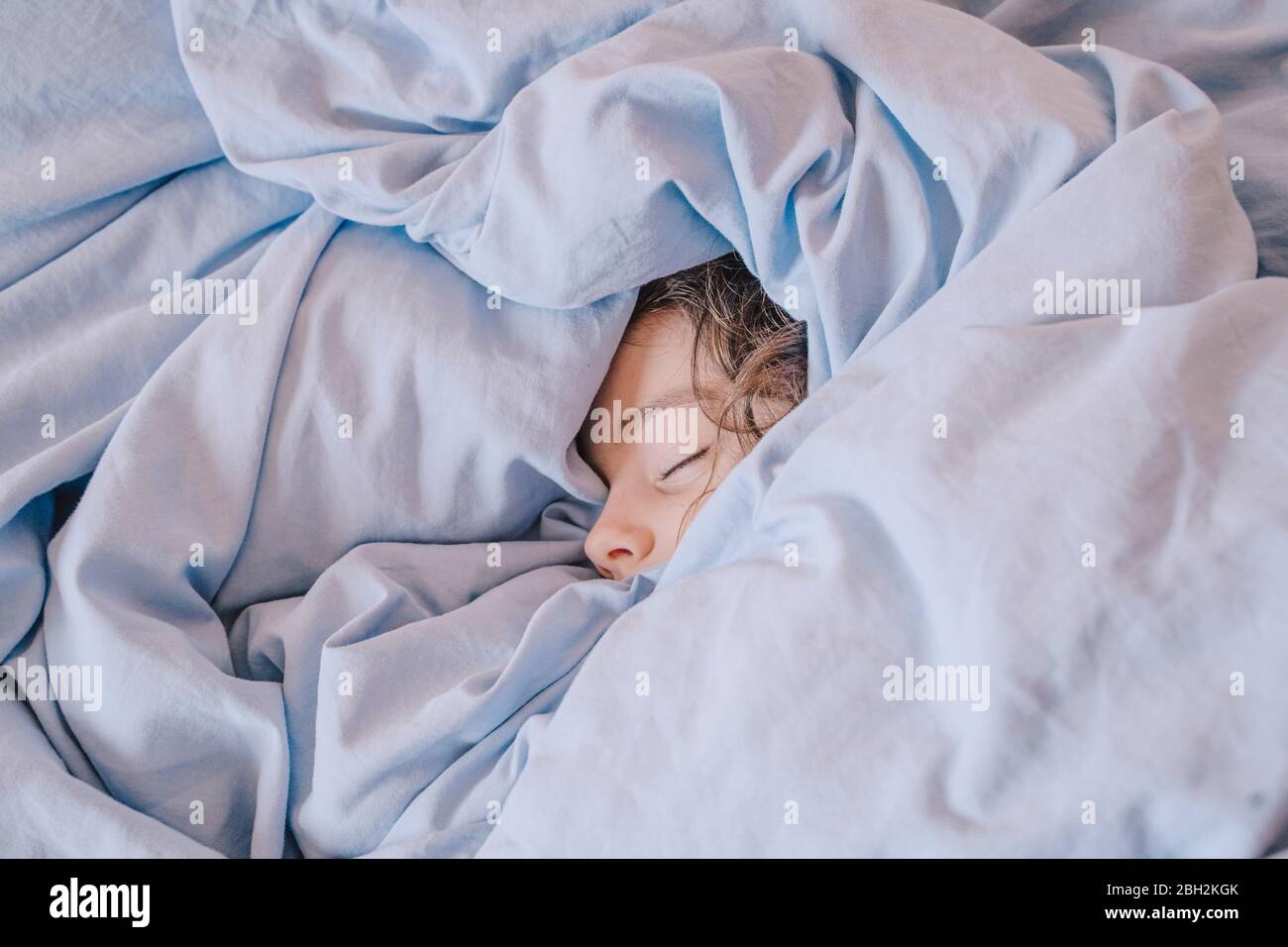 Retrato de una niña dormida acostada bajo una manta Foto de stock