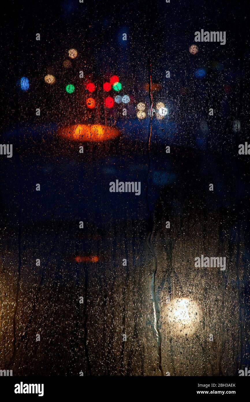 las luces se reflejaron en la ventana del autobús en la noche lluviosa Foto de stock