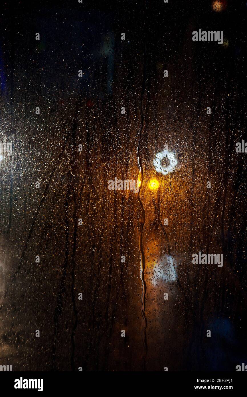 las luces se reflejaron en la ventana del autobús en la noche lluviosa Foto de stock