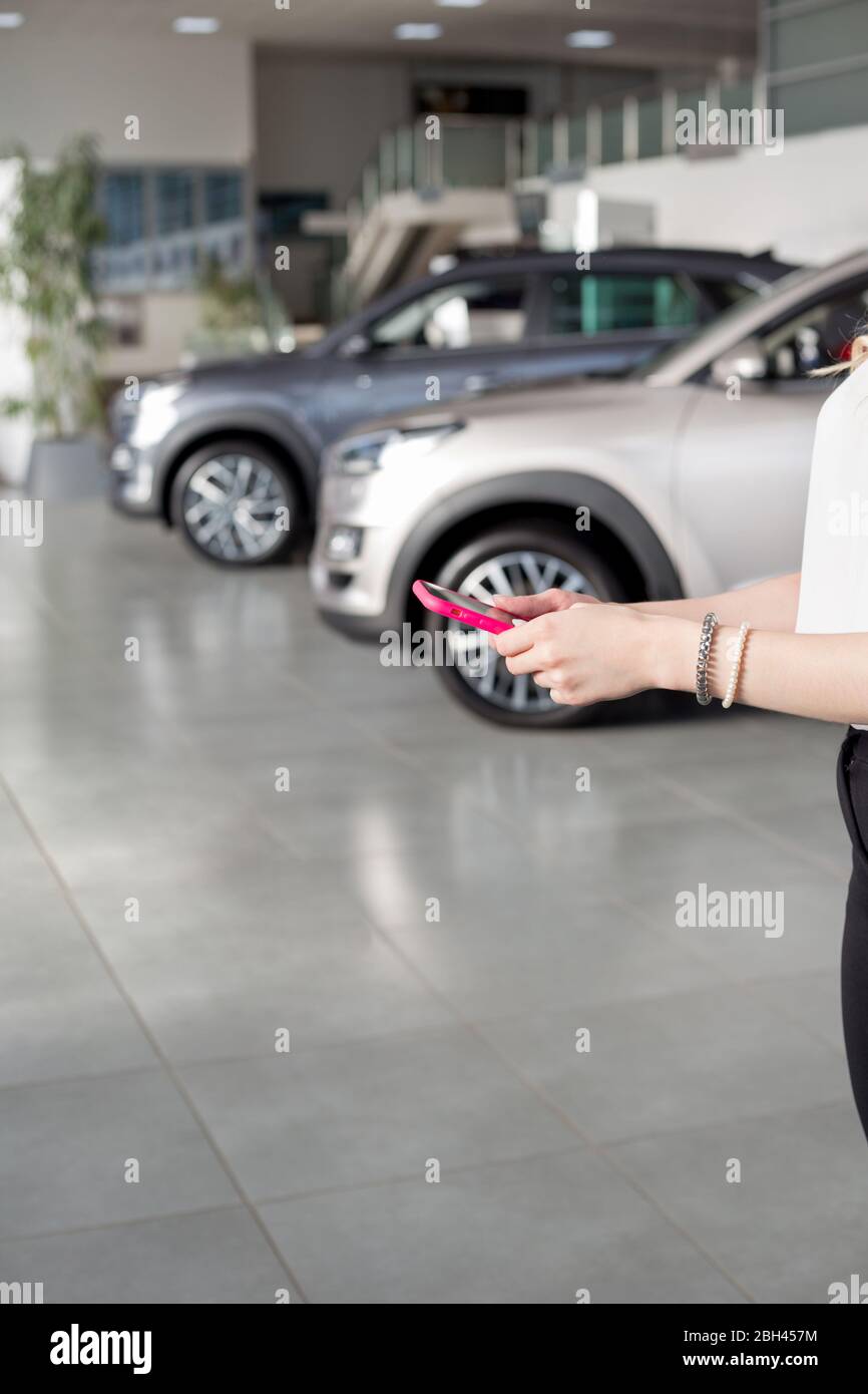 Mujer traficante mediante Mobile teléfono inteligente en el showroom