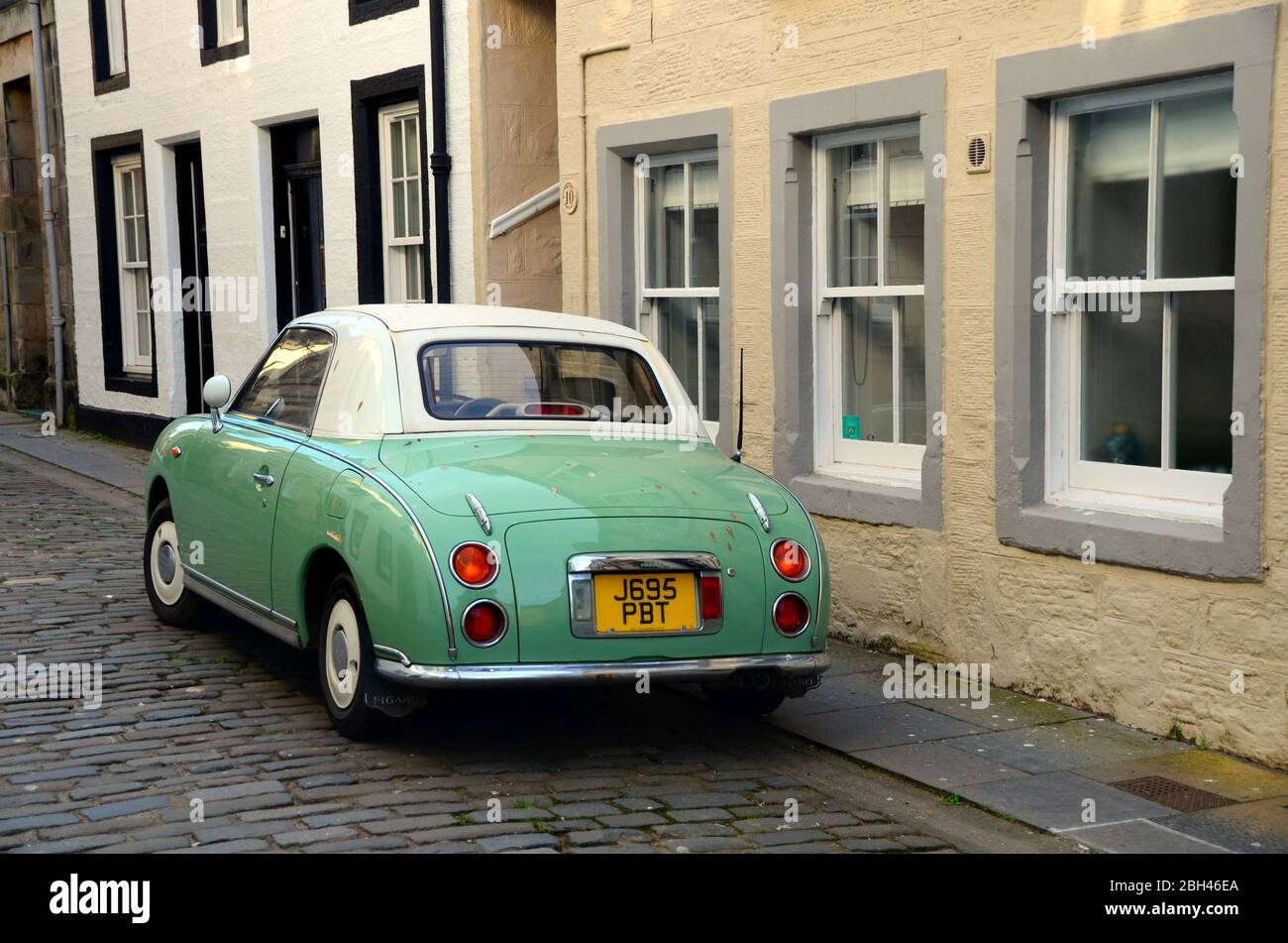 El coche de estilo retro de los años 60, el Nissan Figaro aparcado en una calle adoquinada en el casco antiguo de St andrews, Fifé, Escocia Foto de stock