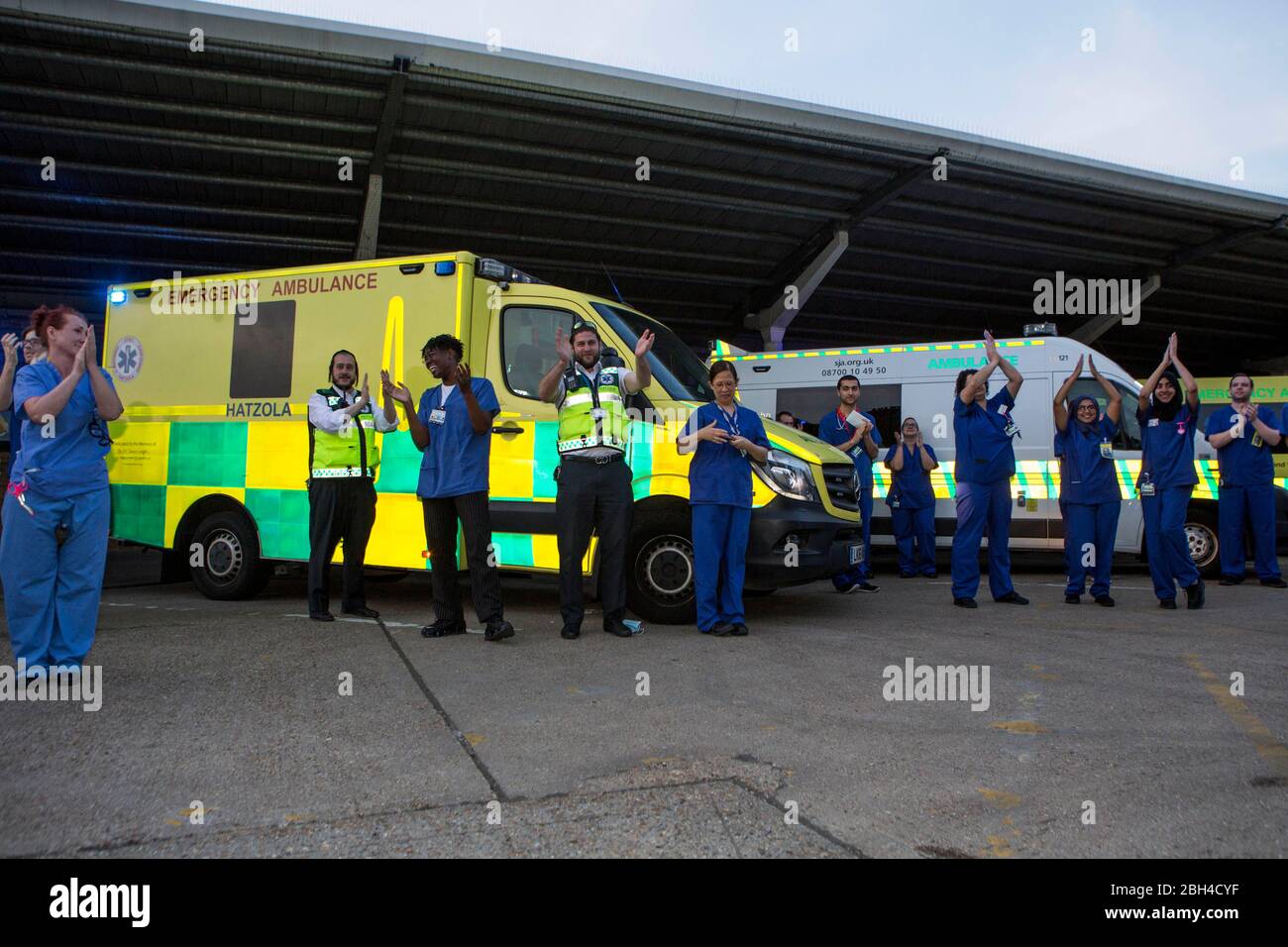 Londres, Reino Unido. 23 de abril de 2020. El personal del hospital sale de Homerton University Hospital Foundation Trust en el este de Londres y es recibido por una pequeña multitud. Aplaudir a los cuidadores, para decir gracias a NHS y otros trabajadores y cuidadores clave. El "bloqueo" continúa en Hackney debido al brote de COVID-19. Crédito: Marcin Nowak/Alamy Live News Foto de stock