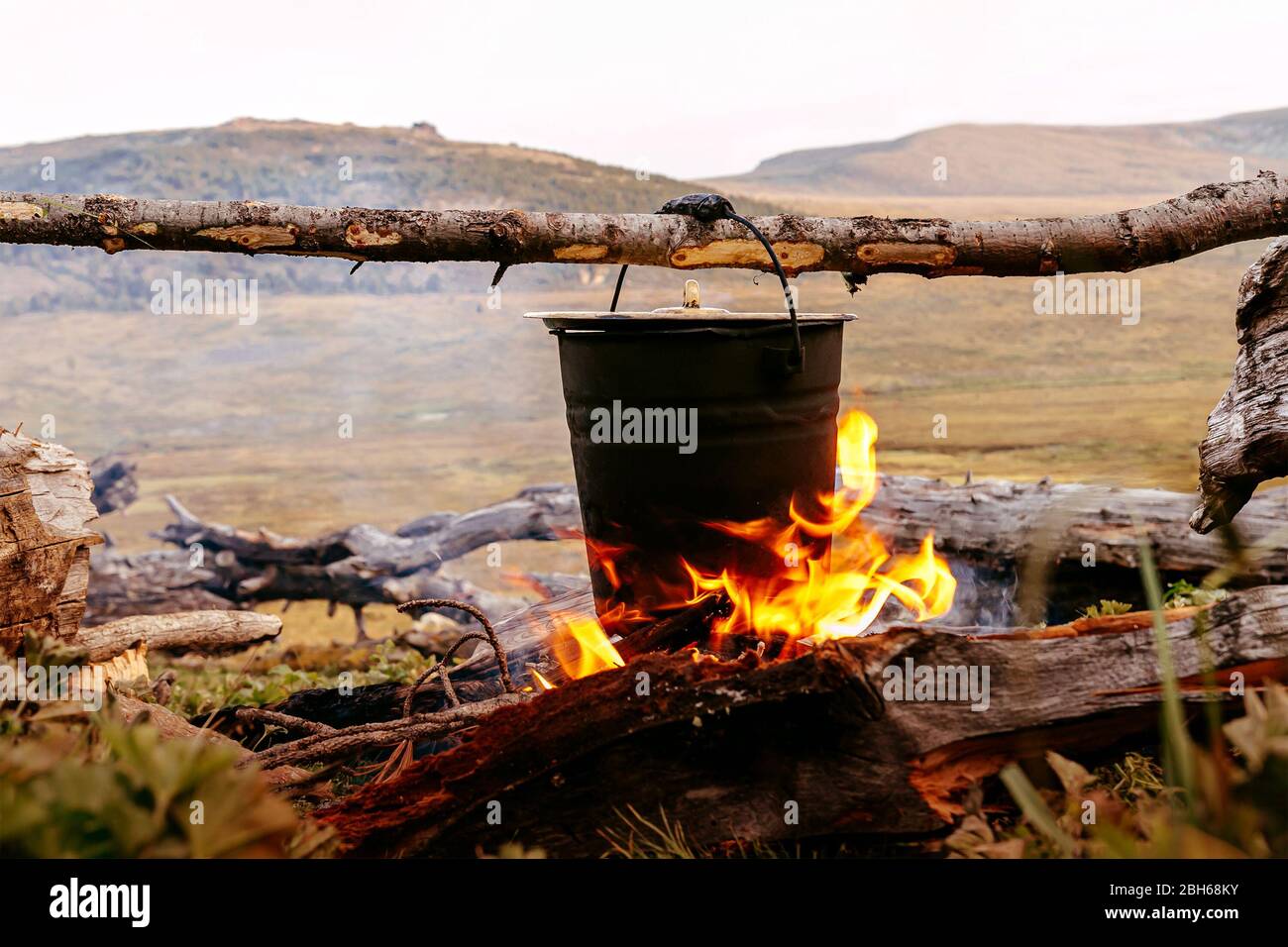 cocinar comida en una olla una chimenea durante el campamento de montaña de senderismo Foto de stock