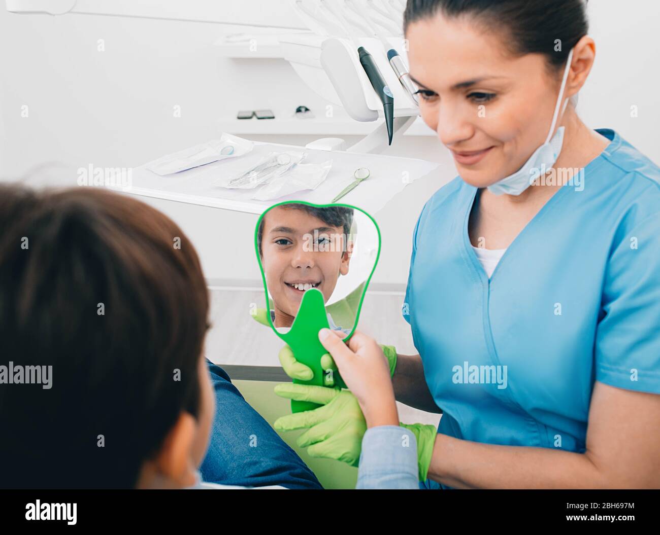 Un chico positivo mirando el espejo en su sonrisa saludable. Tratamiento de dientes infantiles Foto de stock