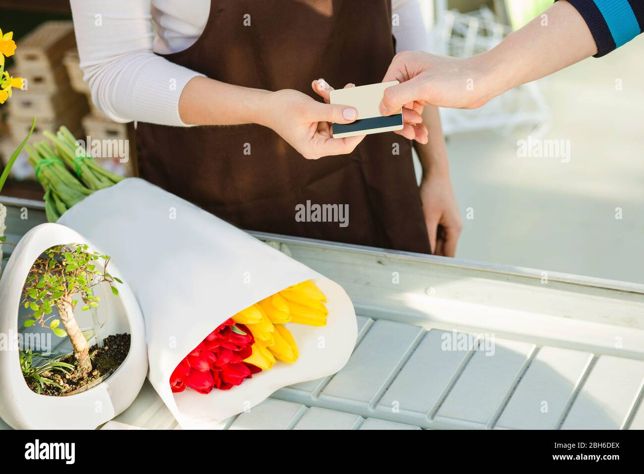mano del comprador dando tarjeta de pago para flores de pago a la vendedora. Pagos sin efectivo Foto de stock