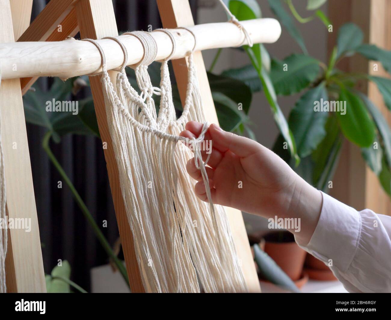 estancia en casa. trabajo durante la cuarentena - una niña en el salón  mural tejiendo las cuerdas en la técnica macrame Fotografía de stock - Alamy