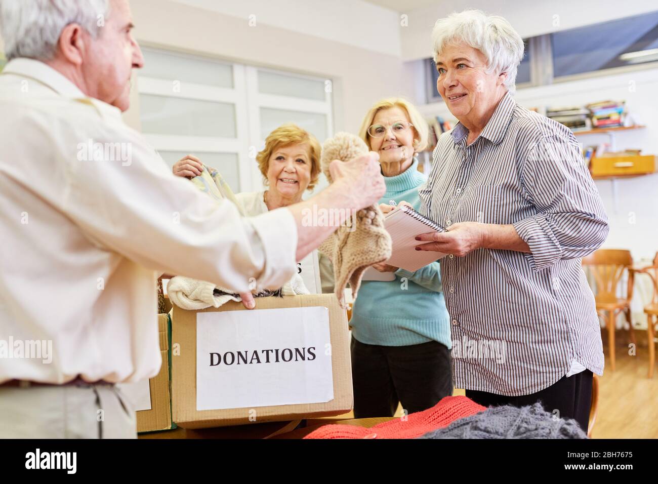 Los ancianos como voluntarios recogen la donación de ropa para los