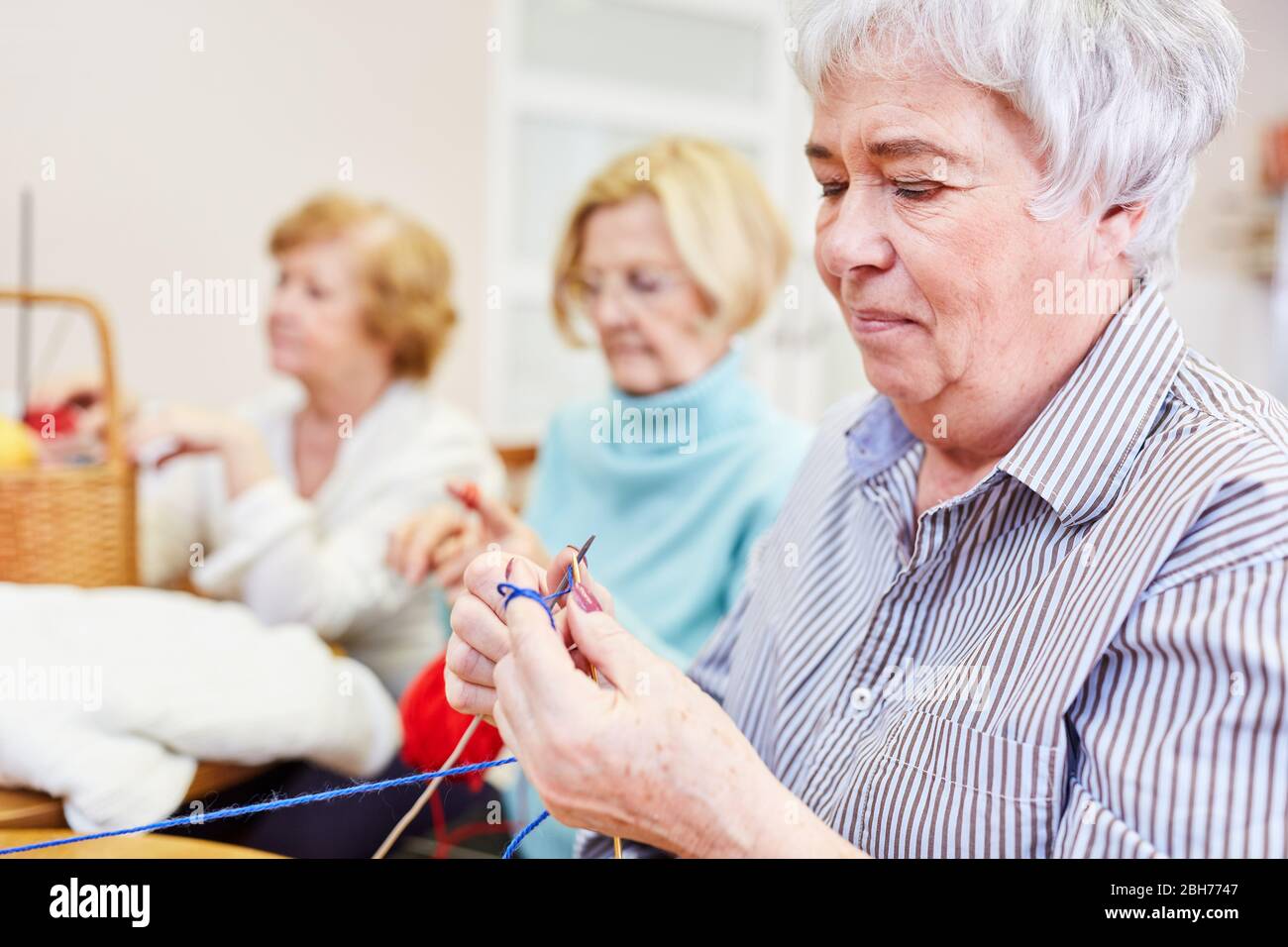Mujer anciana crocheting en un curso de artesanía como hobby o terapia ocupacional Foto de stock