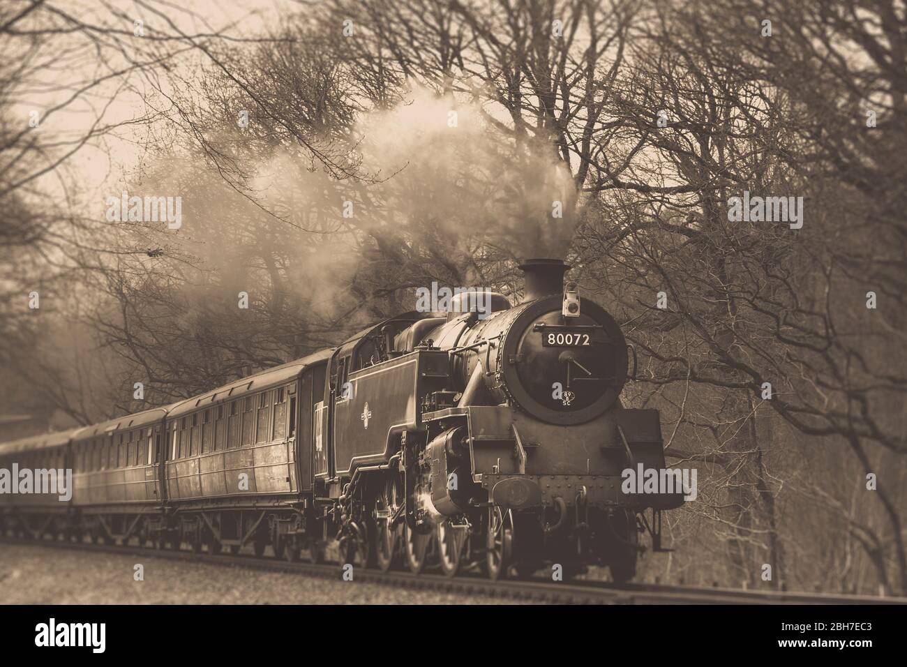 Ángulo bajo, vista sepia del tren de vapor del Reino Unido antiguo que viene en la vía ferroviaria en el campo rural de Worcestershire, línea de patrimonio ferroviario del valle de Severn, Reino Unido Foto de stock