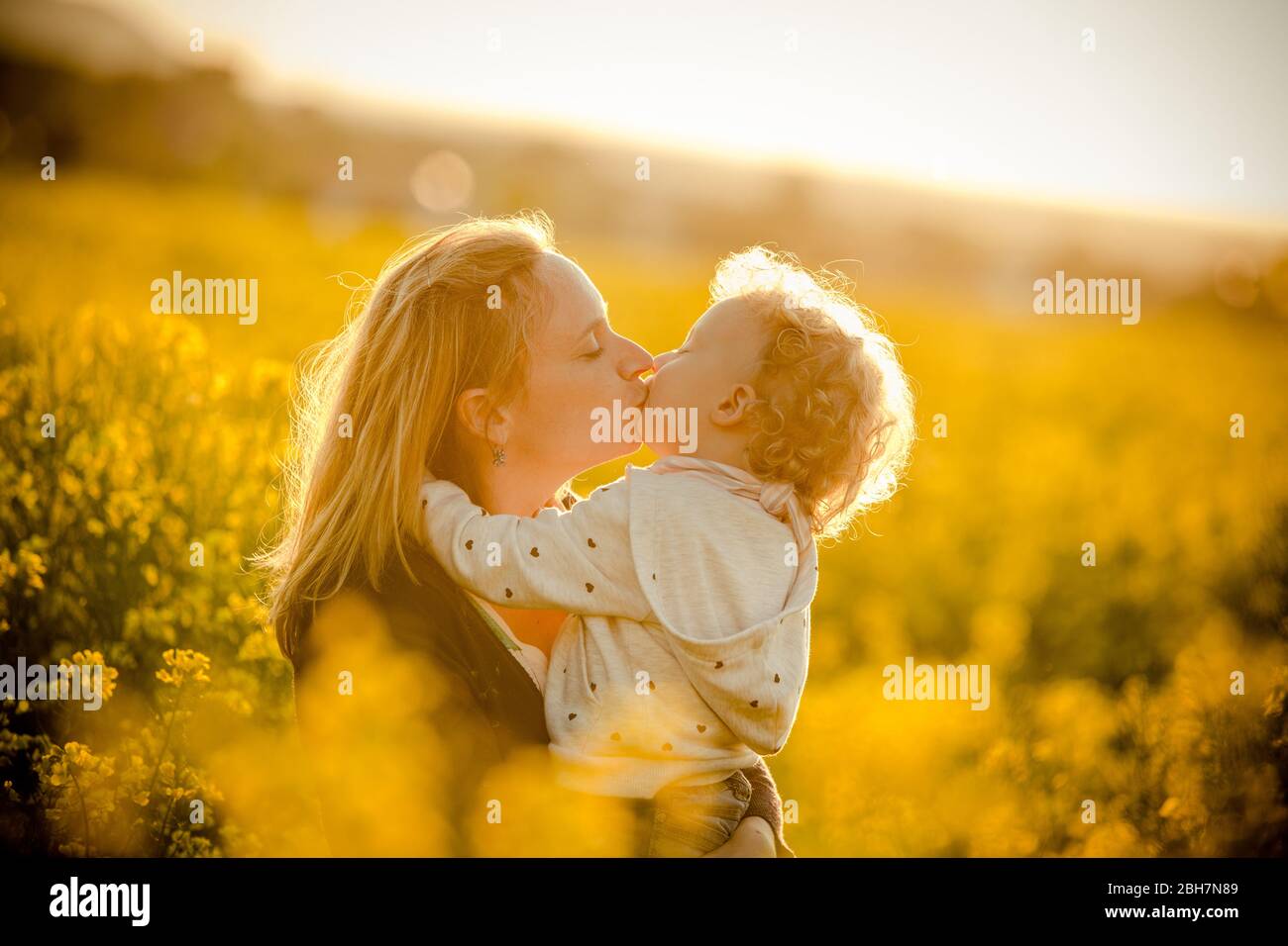 Mamá y su linda hija al aire libre en un campo de flores el día del cumpleaños o de la madre. Foto de stock