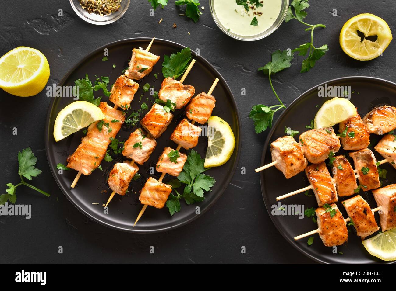 Salmón grillado kebab. Barbacoa pinchos de salmón sobre fondo de piedra negra. Vista superior, laicos plana Foto de stock