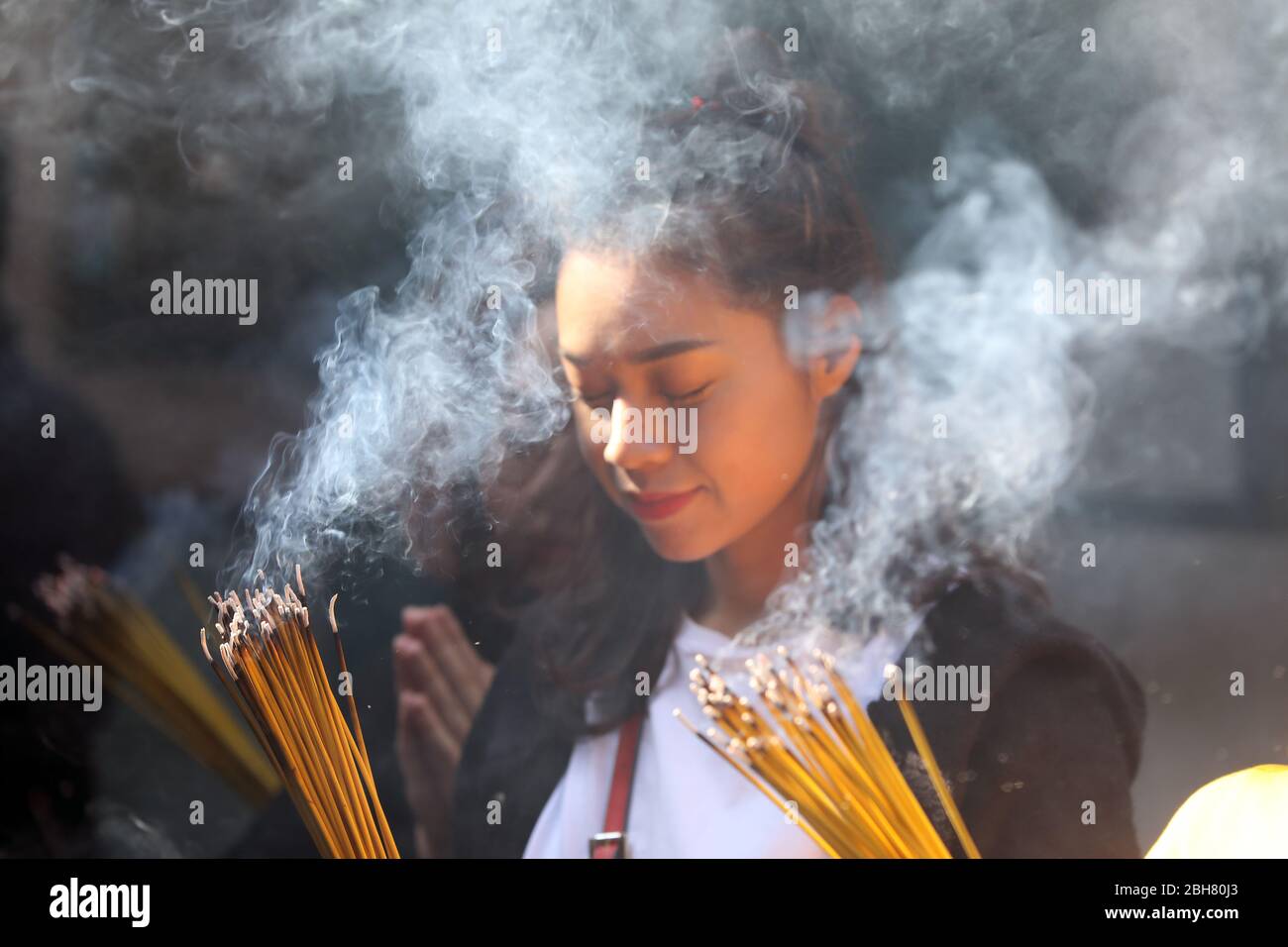 07.12.2019, Macao, , China - joven mujer orando con palos de incienso iluminados en el templo DE A-Ma. 00S191207D210CAROEX.JPG [VERSIÓN MODELO: NO, PROPIEDAD RELE Foto de stock