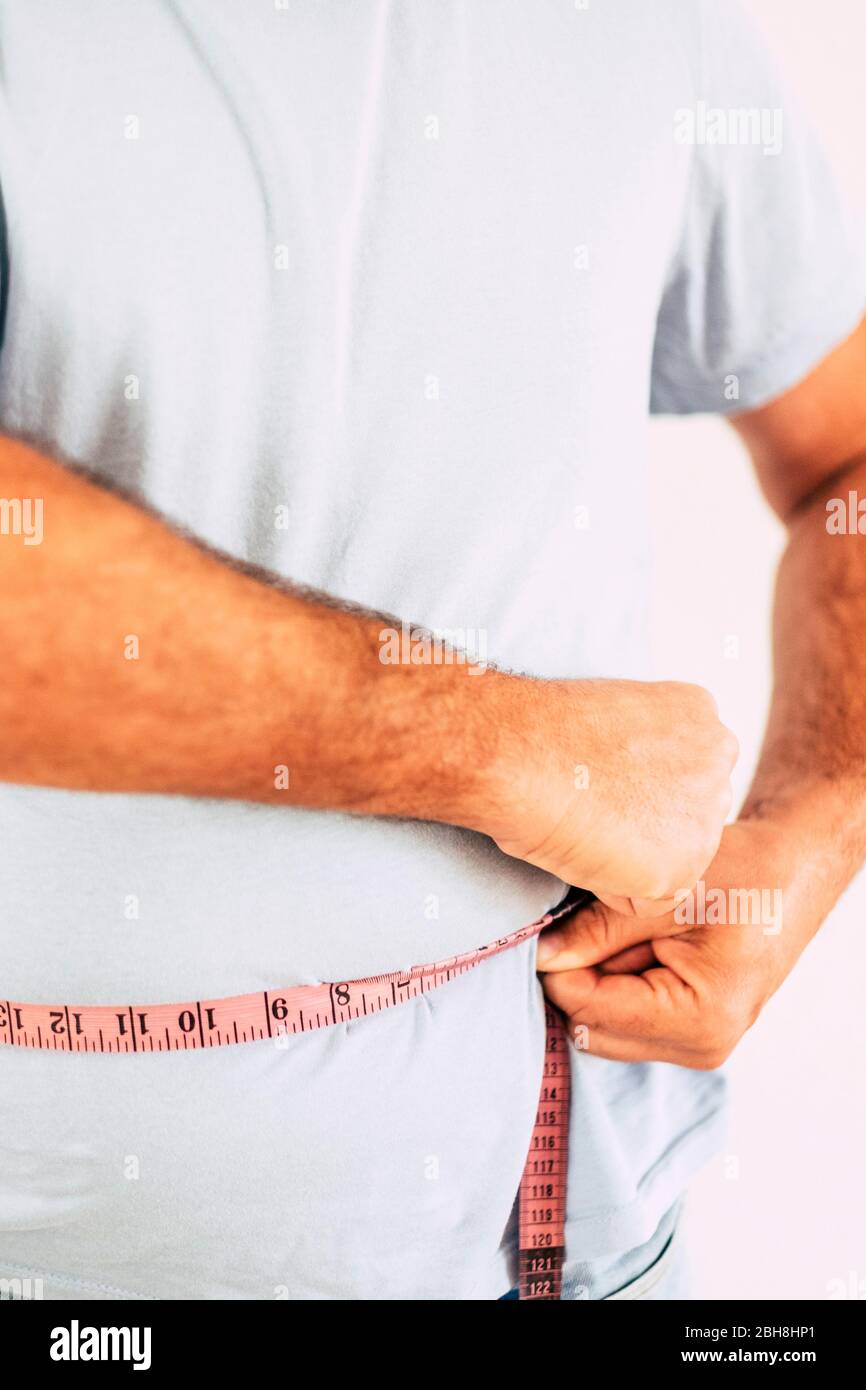 Hombre con camiseta azul tomando medidas del tamaño del vientre - la grasa en la dieta y el concepto para que la gente trate de mantenerse saludable y construir un mejor cuerpo - Foto de stock