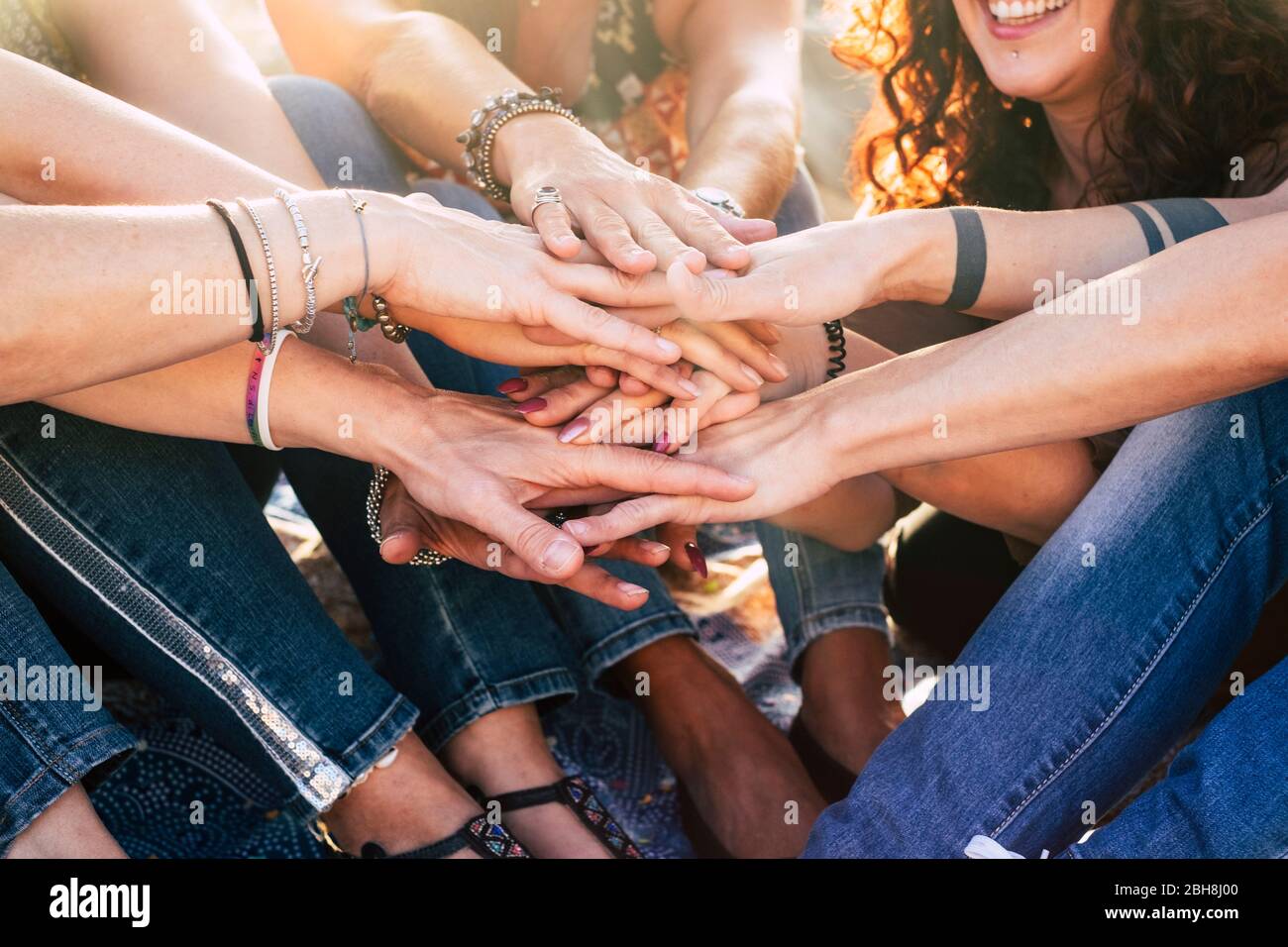 Felicidad y estilo de vida alegre para las chicas del concepto de equipo poniendo las manos juntas para siempre amigos - felicidad y amistad grupo de mujeres sonríe y se divierten con el sol en la retroiluminación Foto de stock