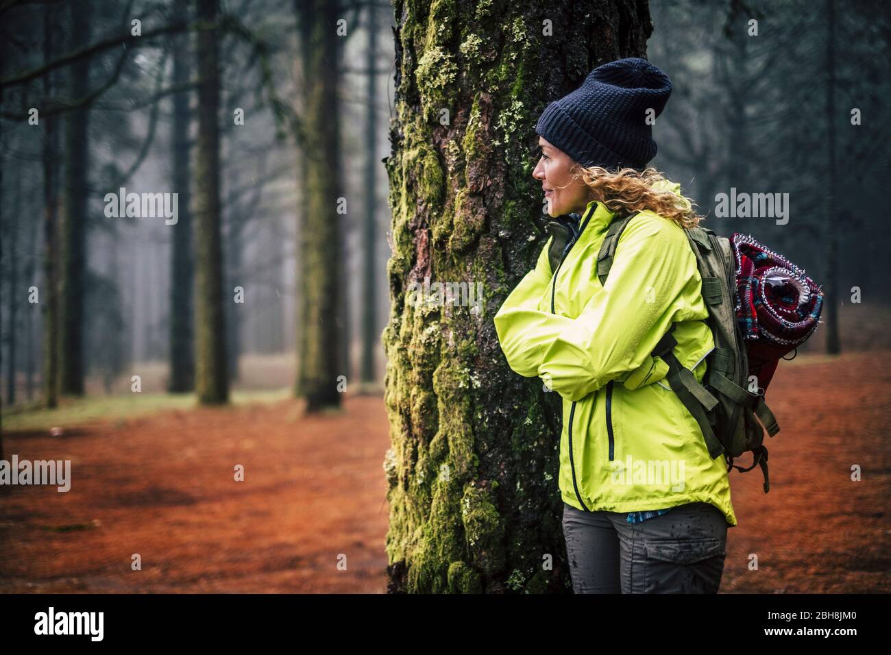 Mujer de edad media caucásica solitaria de pie en el bosque y mirar la hermosa madera a su alrededor - concepto de vacaciones de senderismo alternativo en el salvaje al aire libre - mochilero y la gente de viaje Foto de stock