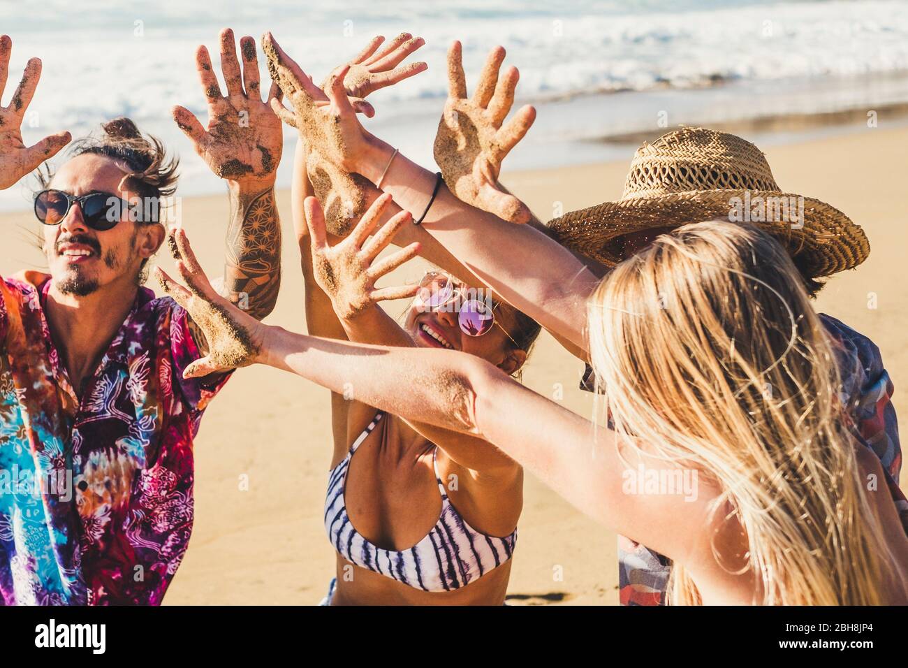 Amigos la gente en vacaciones de verano en la playa muestran sus manos juntos tierra de arena después de un día divertido de actividad en el estilo de vida del mar - grupo hombres y mujeres disfrutan del sol juntos en la amistad Foto de stock