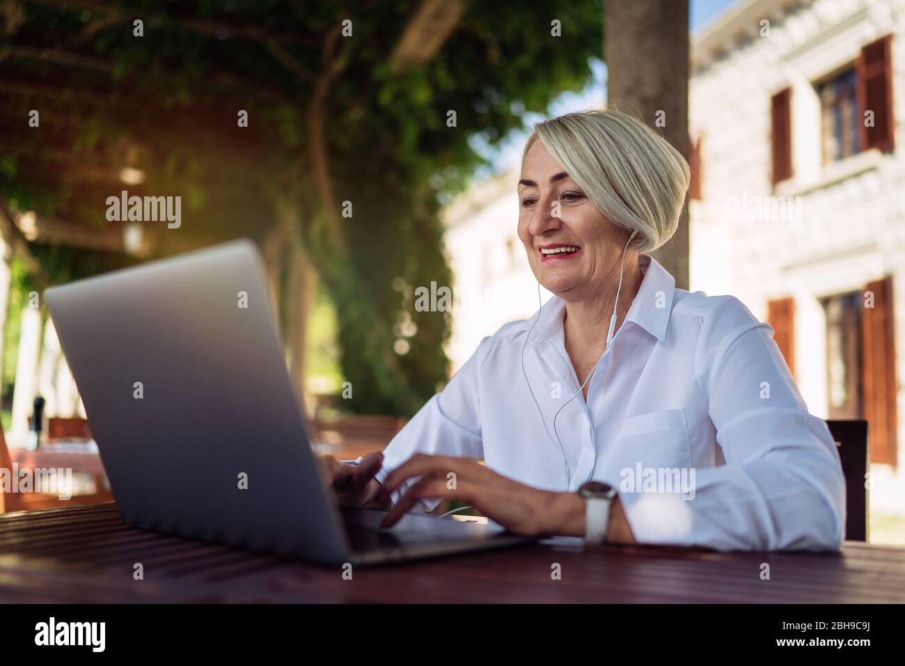 Feliz mujer madura teniendo un video chat a través de la computadora  portátil mientras descansa en el café Fotografía de stock - Alamy