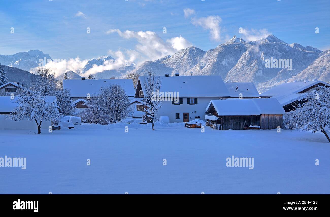 Las casas cubiertas de nieve profunda contra el monte Zugspitze, y los Alpes Ammergauer, Ohlstadt, la Tierra Azul, Alta Baviera, Baviera, Alemania Foto de stock