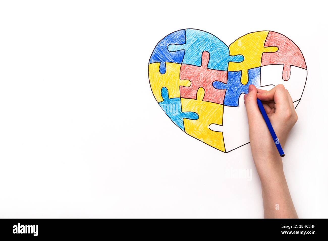 Día Mundial de la conciencia del Autismo. La mano de los niños dibuja el corazón de rompecabezas multicolor. Concepto de atención de salud mental. Foto de stock