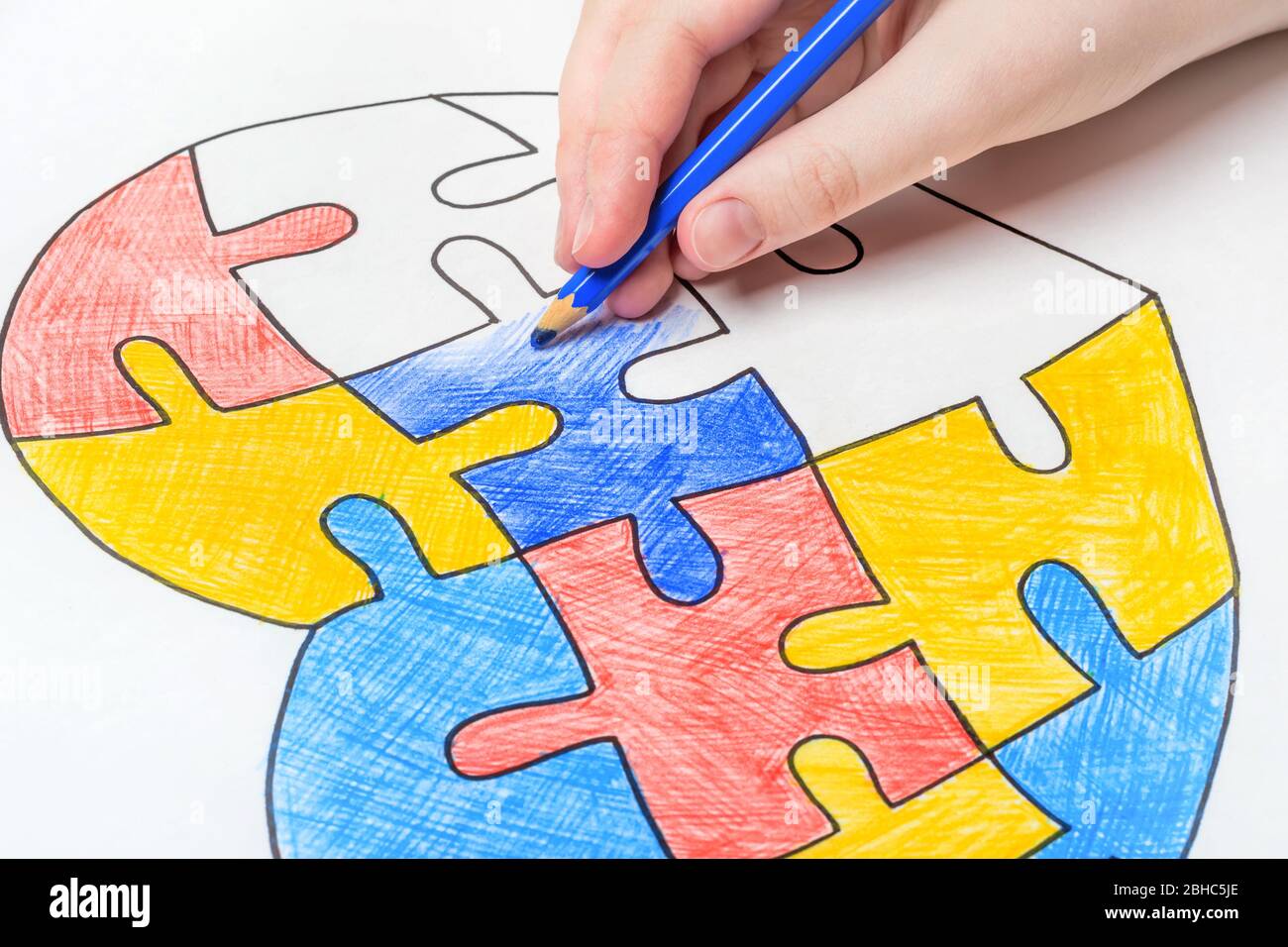 Día Mundial de la conciencia del Autismo. La mano de los niños dibuja el corazón de rompecabezas multicolor. Concepto de atención de salud mental. Foto de stock