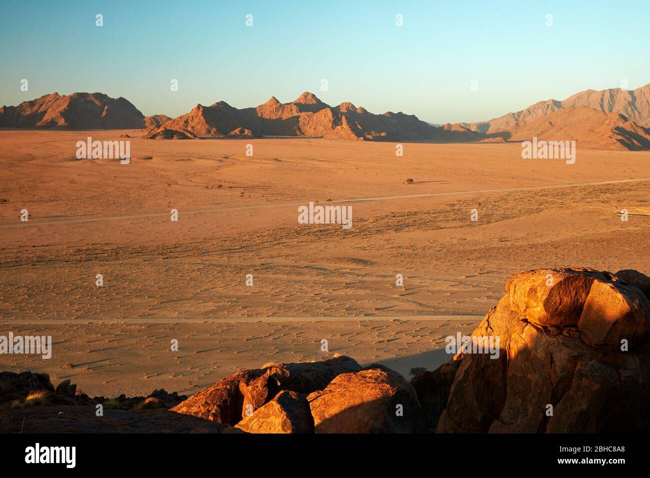 Vista de la llanura y las montañas desde lo alto en un koppie de roca sobre el campamento del desierto, Sesriem, desierto de Namib, Namibia, África Foto de stock