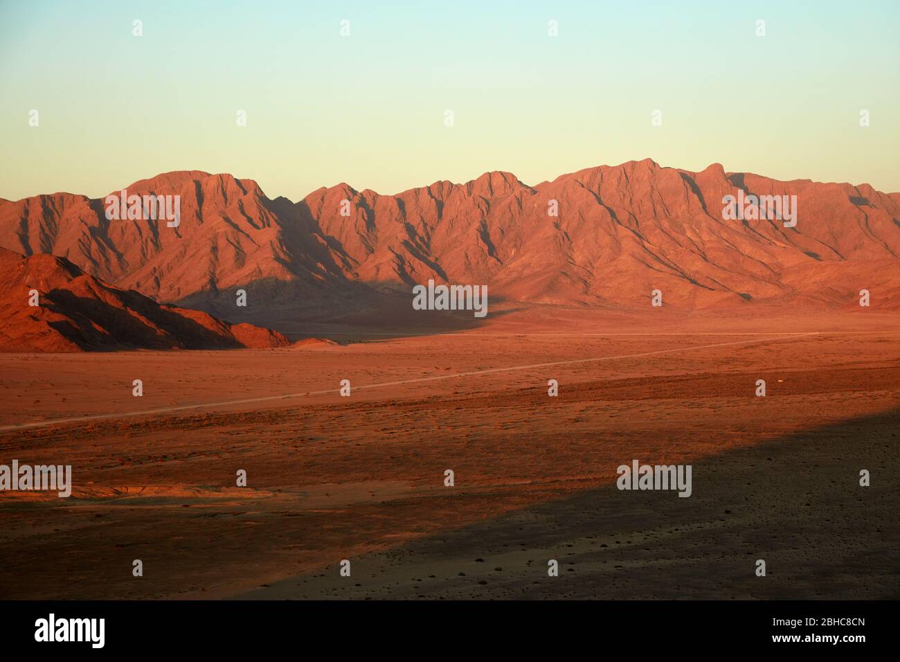 Vista de la luz tardía en la llanura y las montañas desde lo alto en un koppie de roca sobre el campamento del desierto, Sesriem, desierto de Namib, Namibia, África Foto de stock