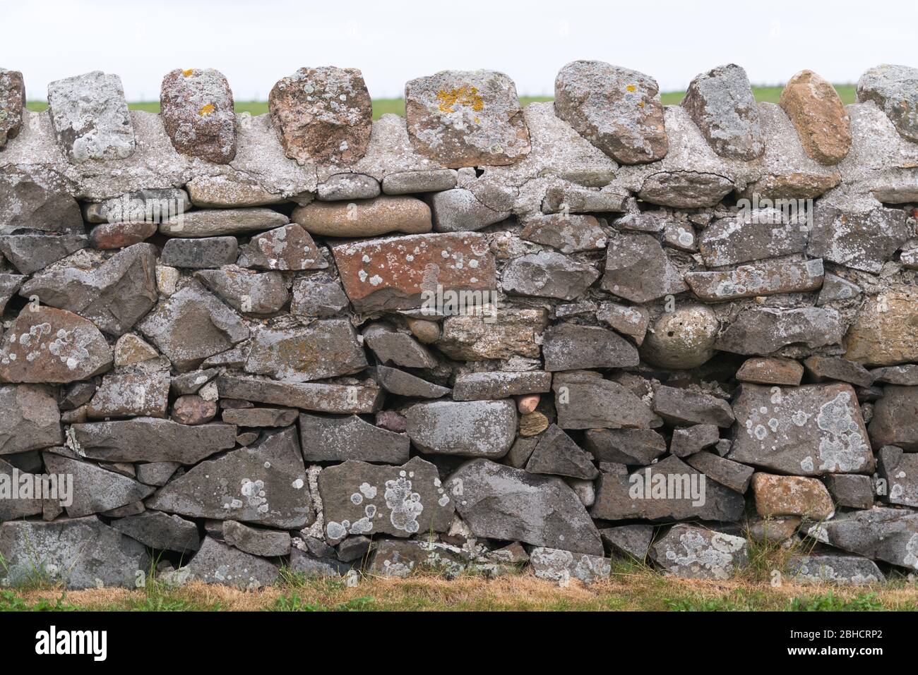 Tradicionalmente puso al azar piedra campo pared con la parte superior de piedra cementada recortado en ningún contexto Foto de stock