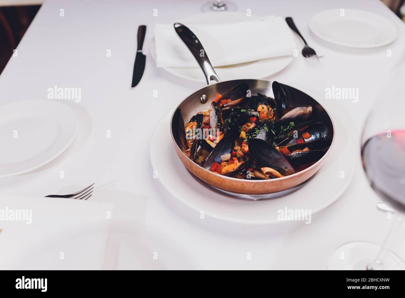 Mejillones hervidos en un plato de cocina de cobre sobre fondo blanco de primer plano Foto de stock