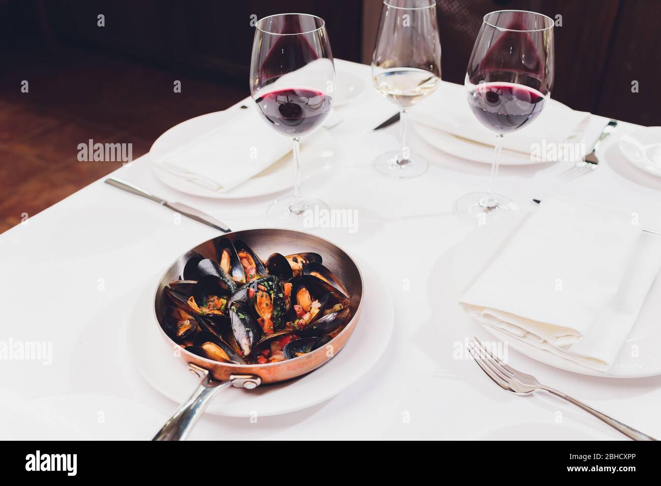 Mejillones hervidos en un plato de cocina de cobre sobre fondo blanco de primer plano Foto de stock