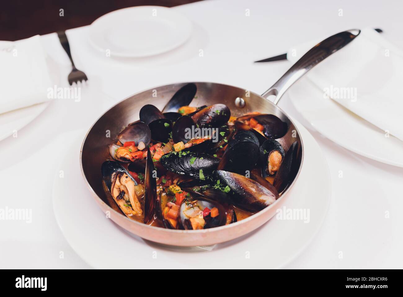 Mejillones hervidos en un plato de cocina de cobre sobre fondo blanco de primer plano Foto de stock