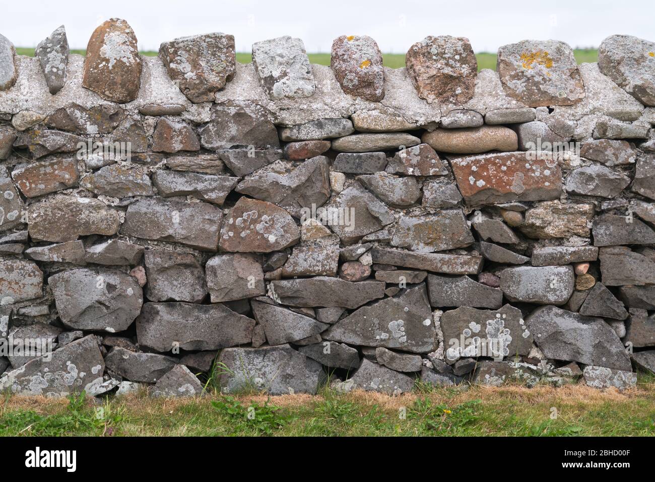 Tradicionalmente puso al azar piedra campo pared con la parte superior de piedra cementada recortado en ningún contexto Foto de stock