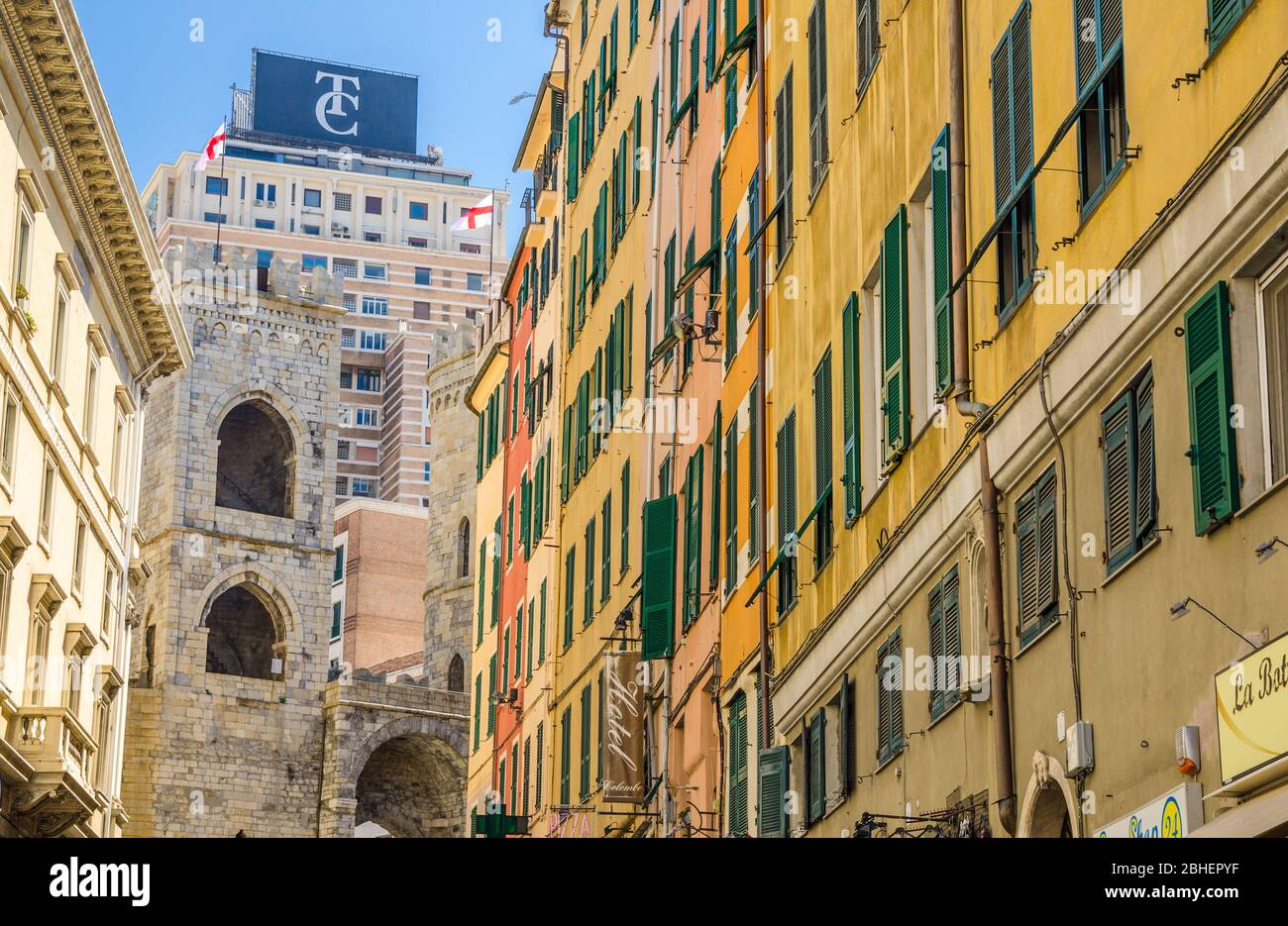 Génova, Italia, 11 de septiembre de 2018: Torre medieval Porta Soprana puerta, edificios coloridos con persianas en las ventanas, rascacielos moderno de fondo en el centro histórico de la vieja ciudad europea Génova, Liguria Foto de stock