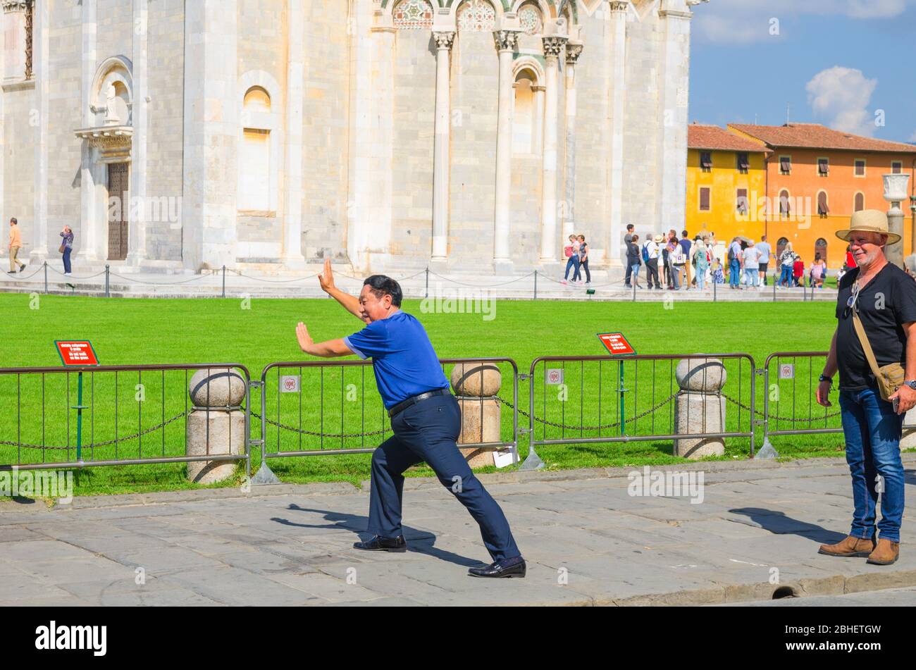 Pisa, Italia, 14 de septiembre de 2018: Turistas viajeros caucásicos y asiáticos chinos, los hombres japoneses están posando, divertirse, hacer fotos estereotipadas, pretendiendo celebrar la famosa Torre inclinada, Toscana Foto de stock