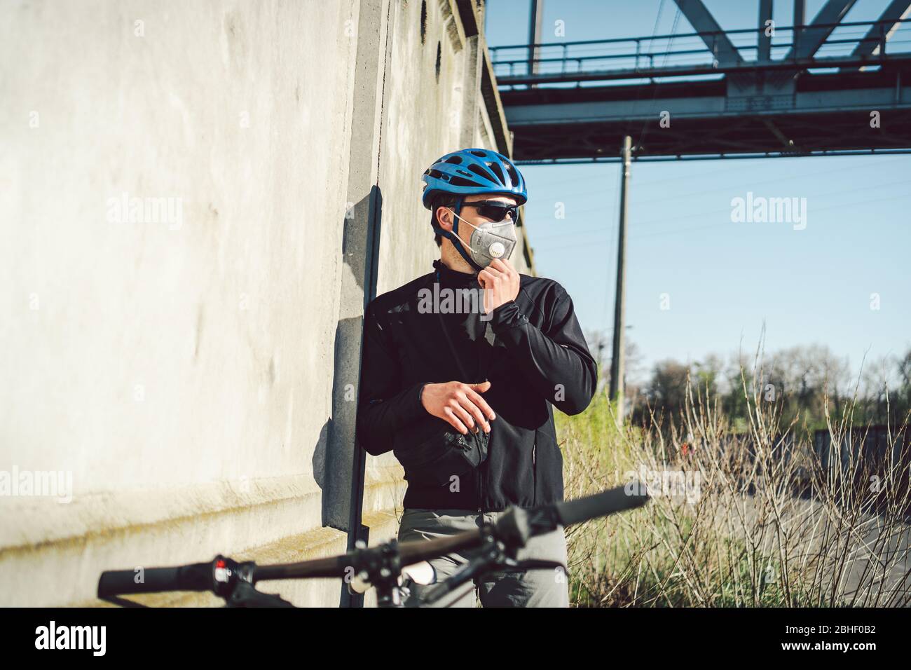 Ciclista en máscara debido a la niebla en la ciudad. Mensajero de la  bicicleta haciendo una entrega. Hombre con mascarilla covid 19 coronavirus.  Ciclista en máscara de contaminación de Fotografía de stock -