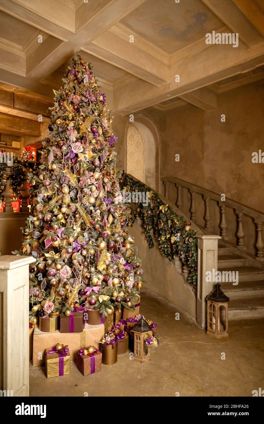 Interior de la casa de Navidad con árbol y escaleras. Salón tradicional en  casa de campo decorado con luces y velas. Gran árbol de Navidad. Navidad  Fotografía de stock - Alamy