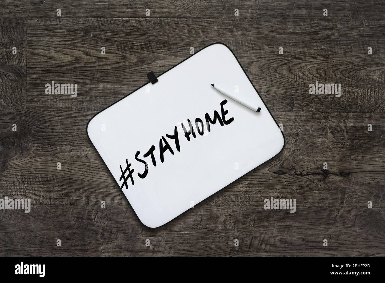 Hash Tag # Stay Home escrito en una pizarra blanca debido a la pandemia de Covid-19, sobre un fondo de madera Foto de stock