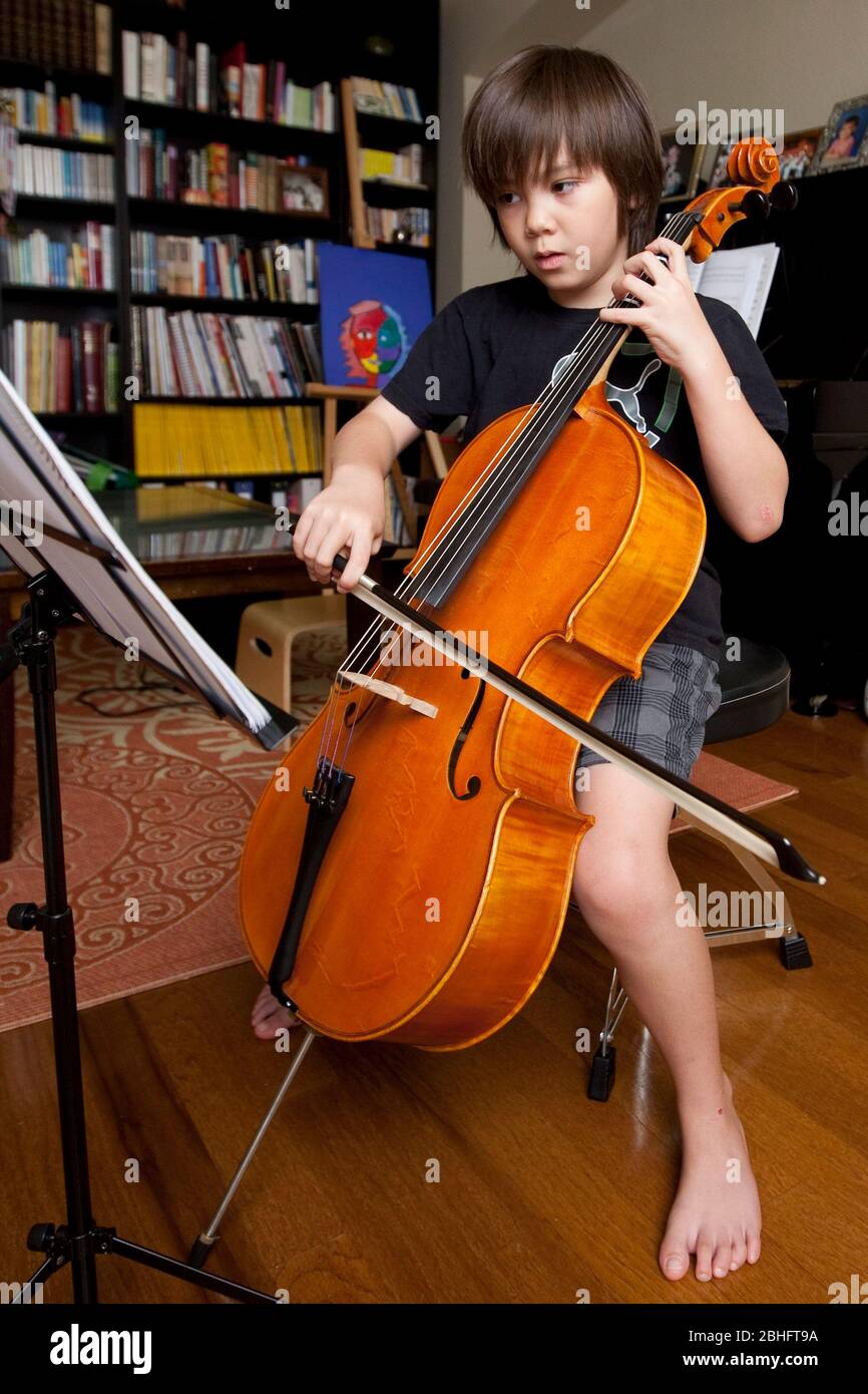 Austin Texas USA, 2012: Un niño japonés-americano de 8 años practica tocando violonchelo y leyendo partituras mientras está en casa. ©Marjorie Kamys Cotera/Daemmrich Photography Foto de stock
