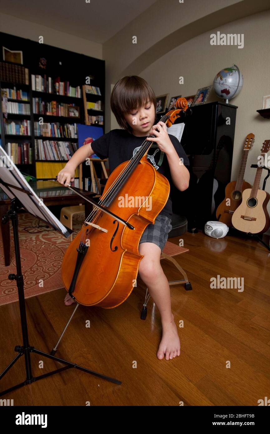 Austin Texas USA, 2012: Un niño japonés-americano de 8 años practica tocando violonchelo y leyendo partituras mientras está en casa. ©Marjorie Kamys Cotera/Daemmrich Photography Foto de stock
