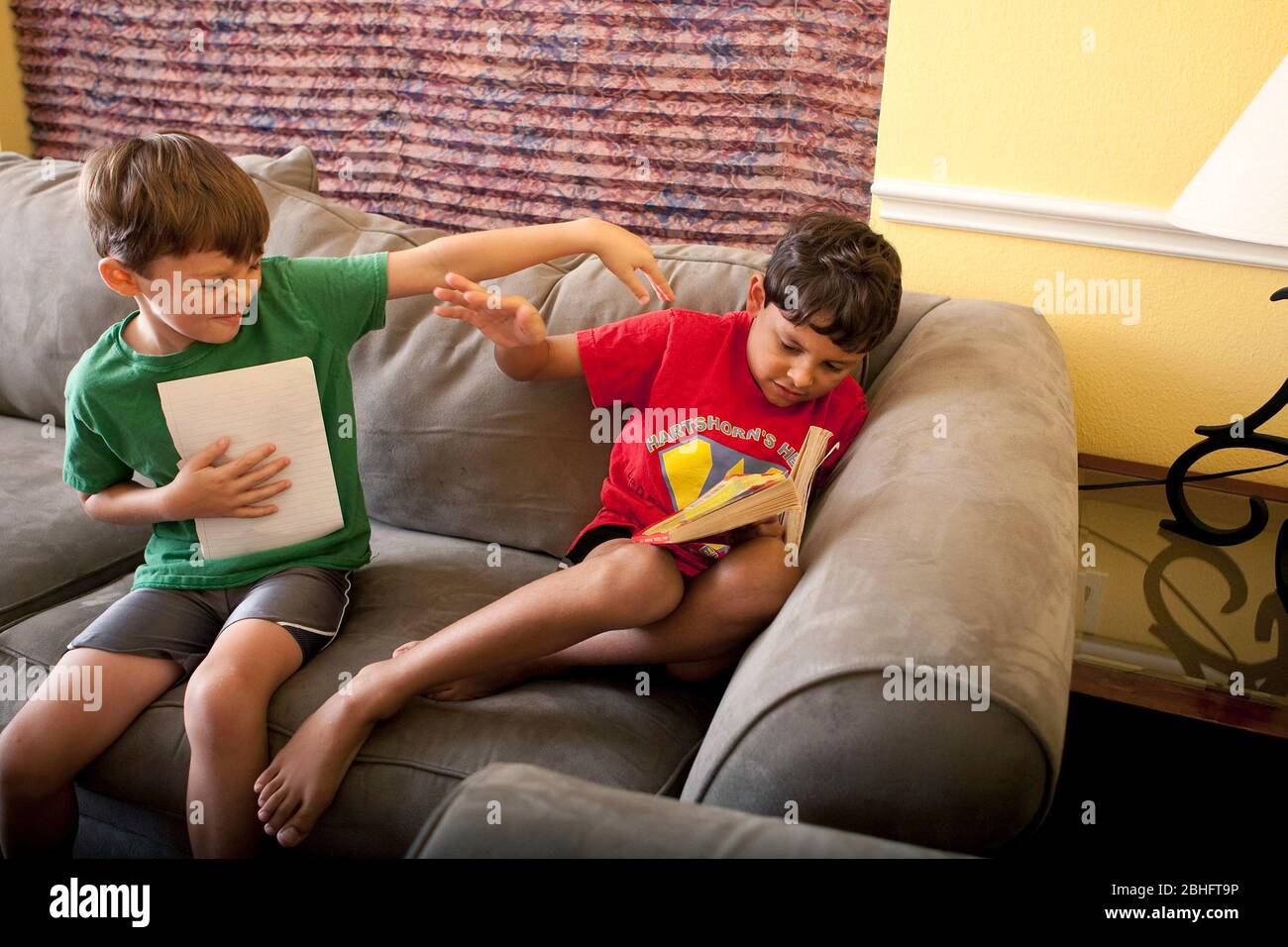 Austin Texas USA, 2012: Un niño hispano de 6 años molesta a su hermano de 8 años que está tratando de leer un libro en casa. ©Marjorie Kamys Cotera/Daemmrich Photography Foto de stock