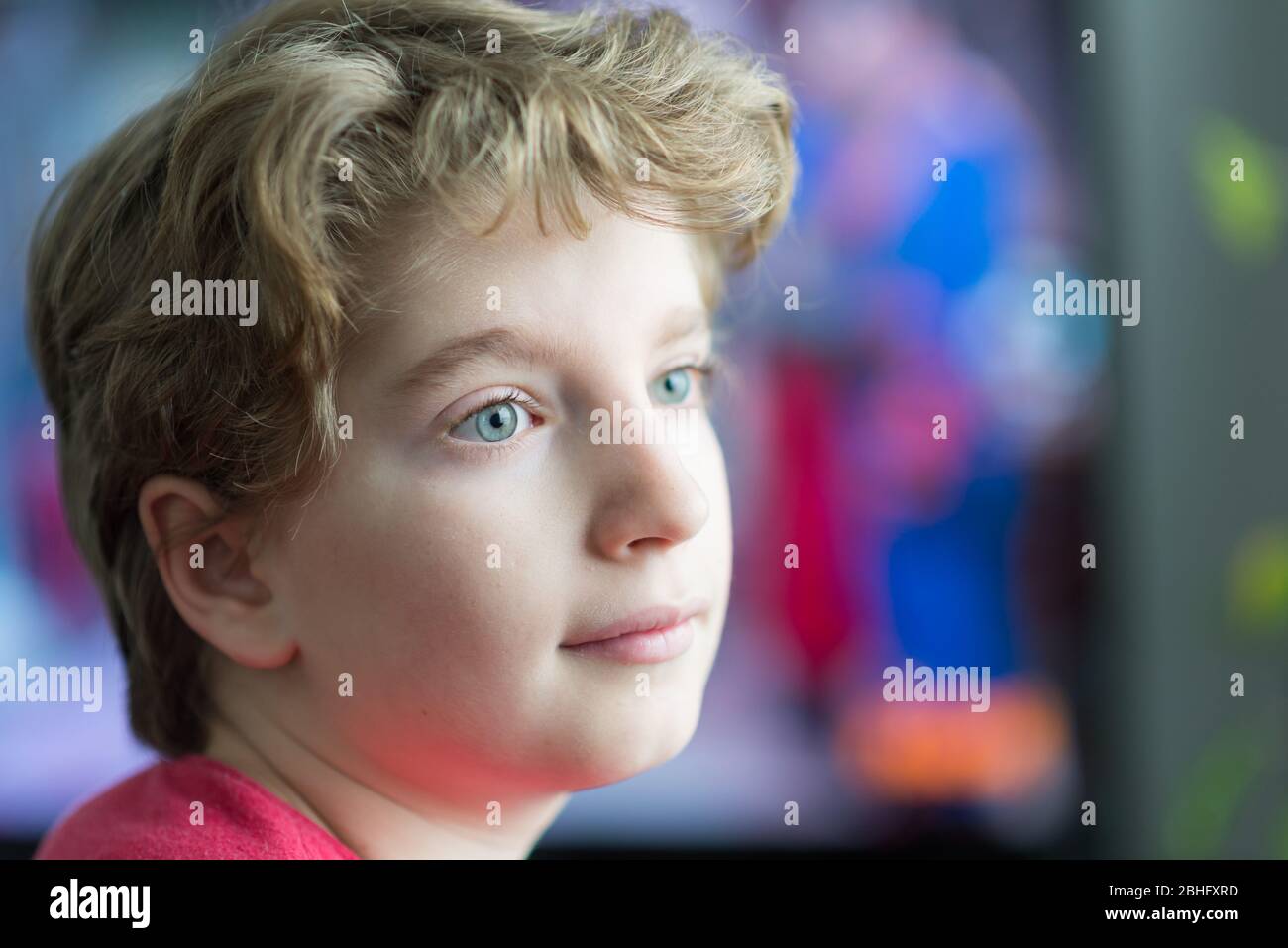 Retrato de un niño con ojos azules, fondo colorido y borroso Foto de stock